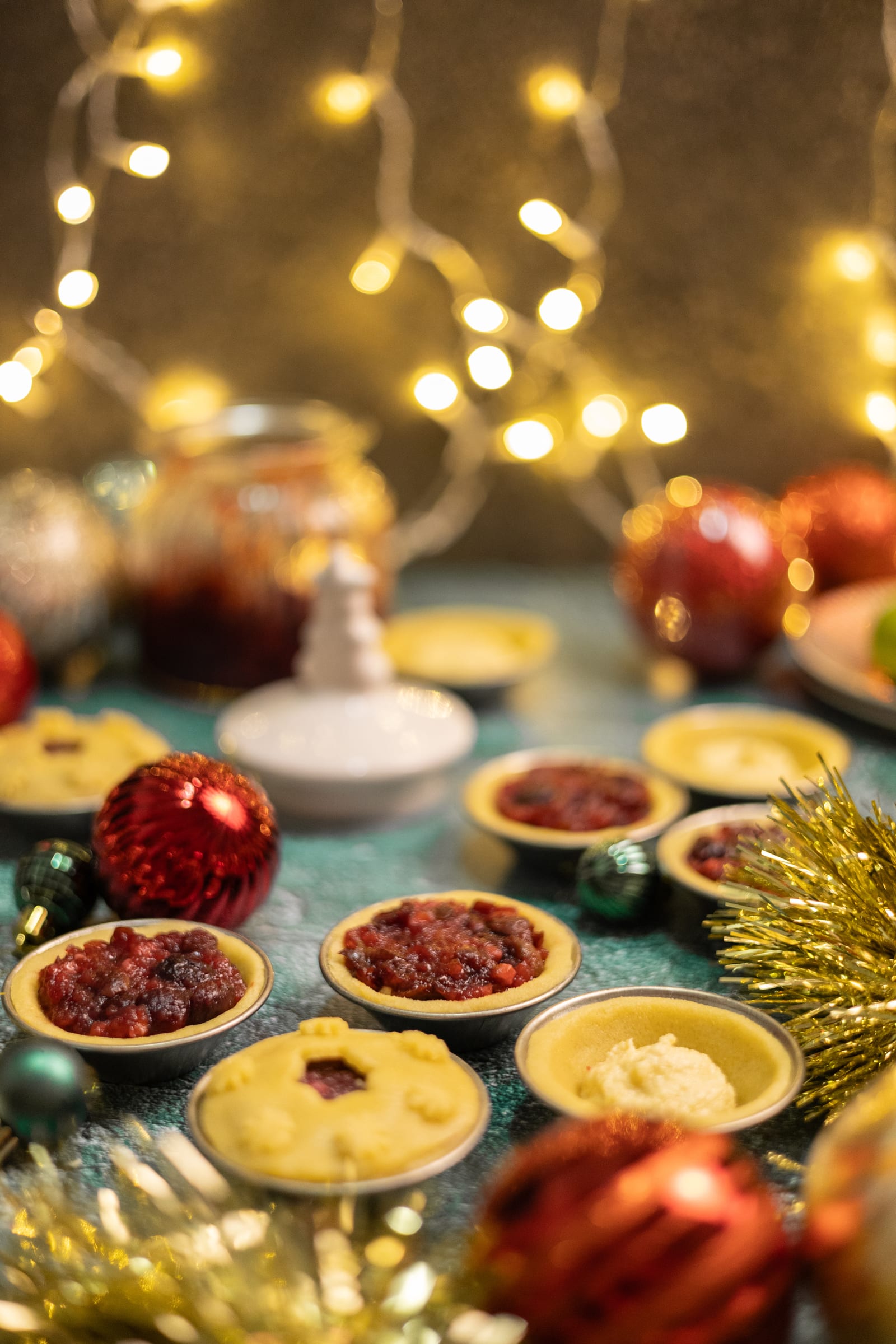 Cherry and amaretto pies in tins under fairy lights, with red baubles