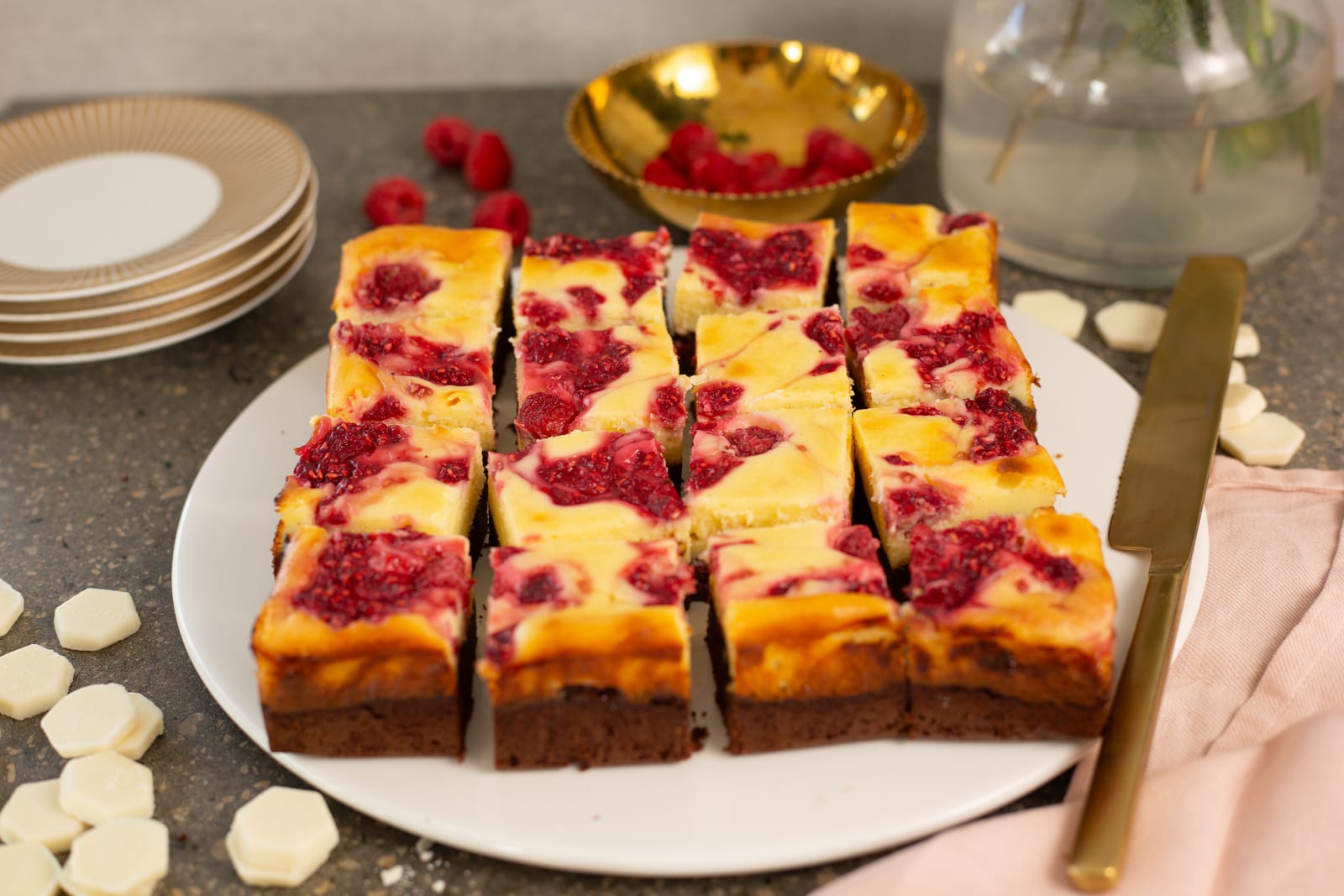 Raspberry ripple cheesecake brownie bars cut into squares on a white plate