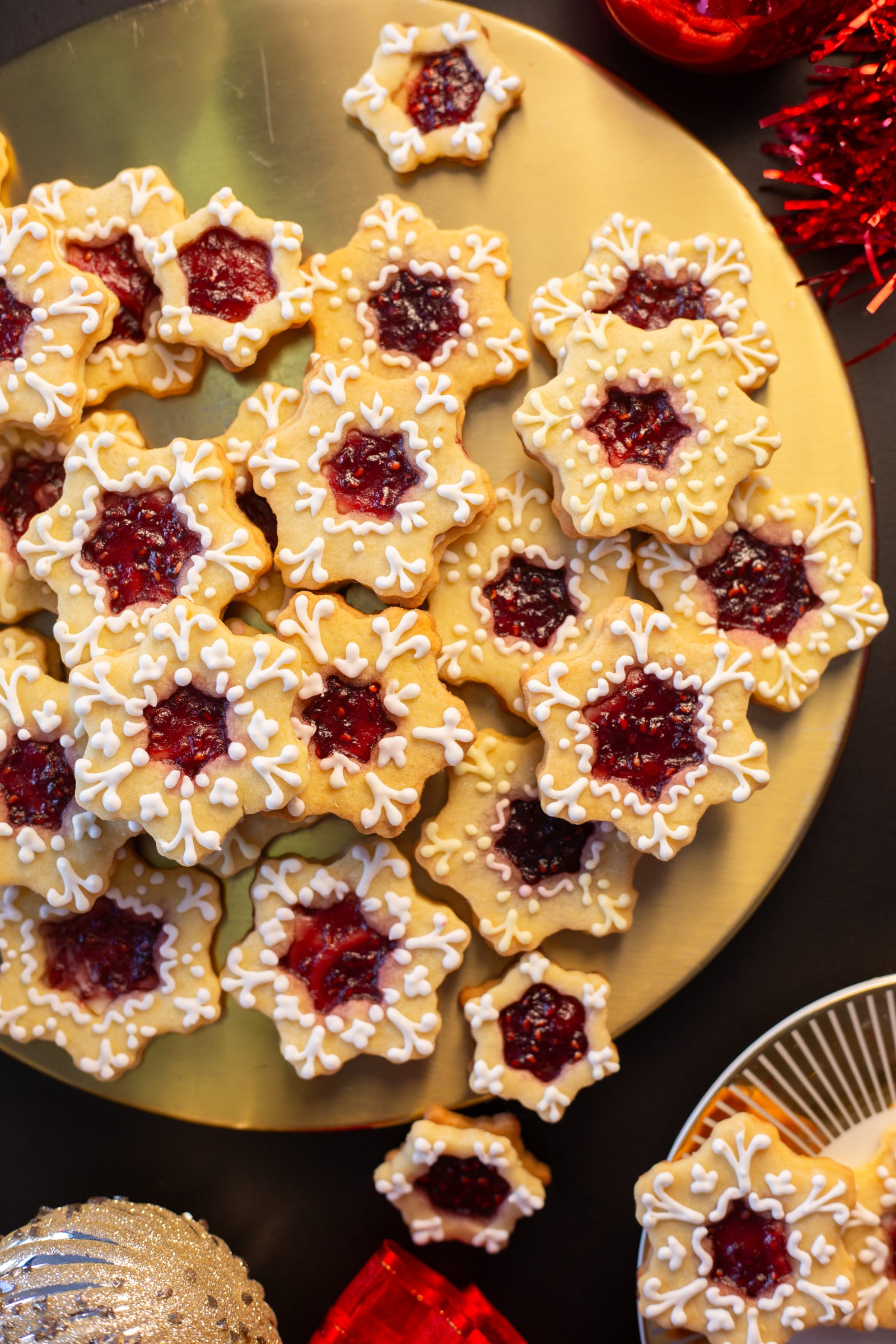 Star-shaped lemon and raspberry Linzer cookies piled on a gold platter, seen from above