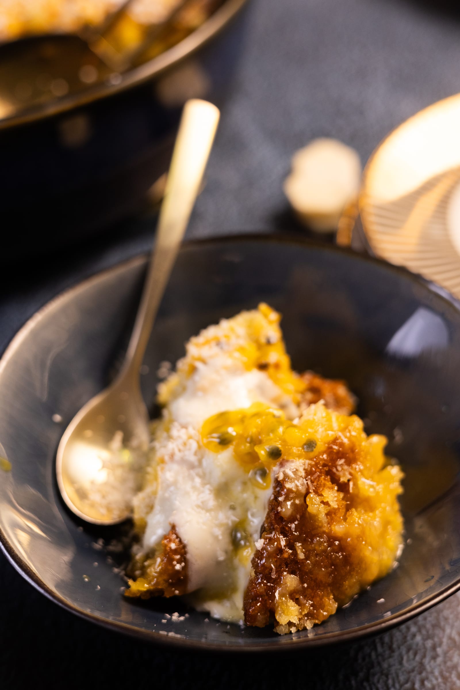 A bowl of pudding with coconut cream and a gold spoon