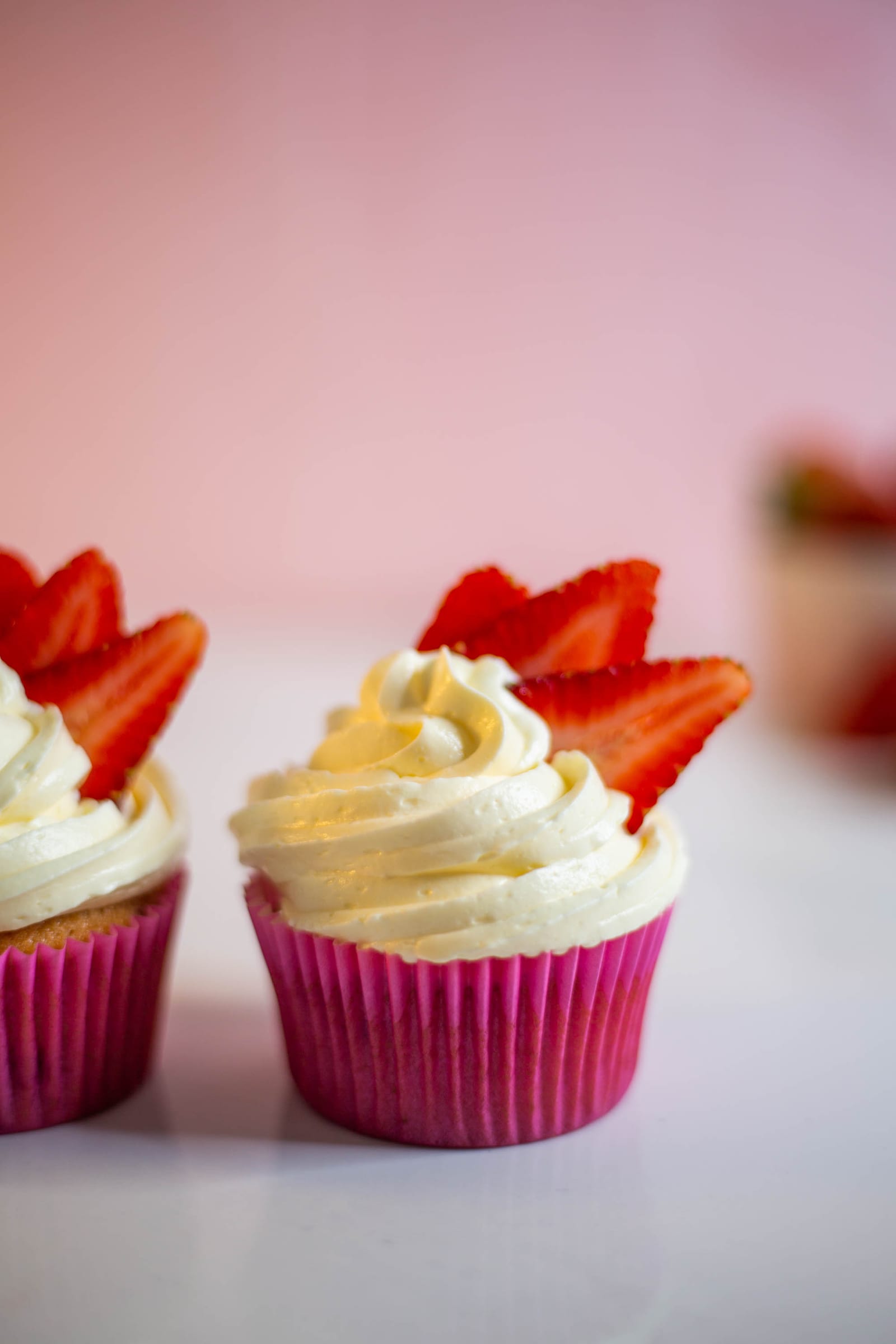 Close-up of two strawberry and white chocolate cupcakes in pink cases