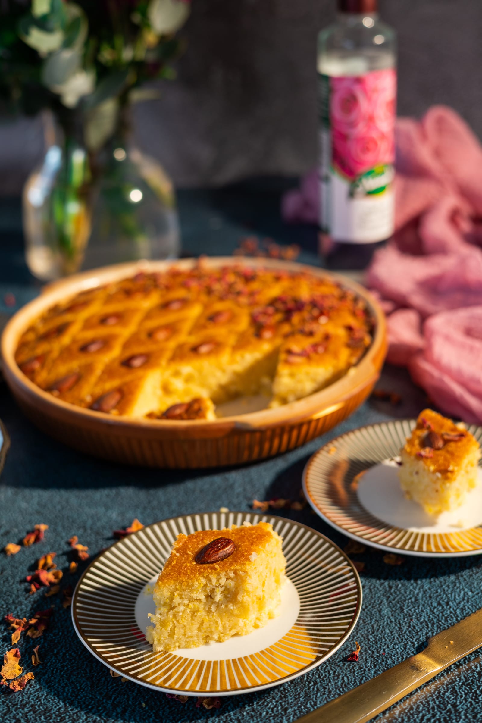A piece of basbousa on a plate in front of the dish