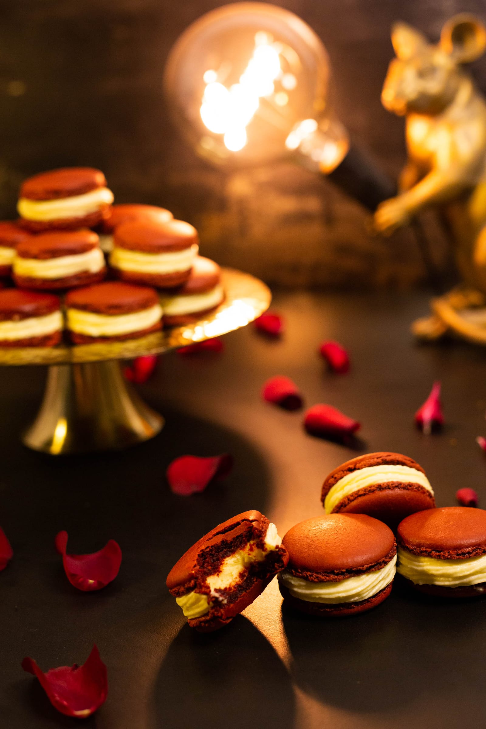 Bitten red velvet macarons in front of the gold stand and lamp