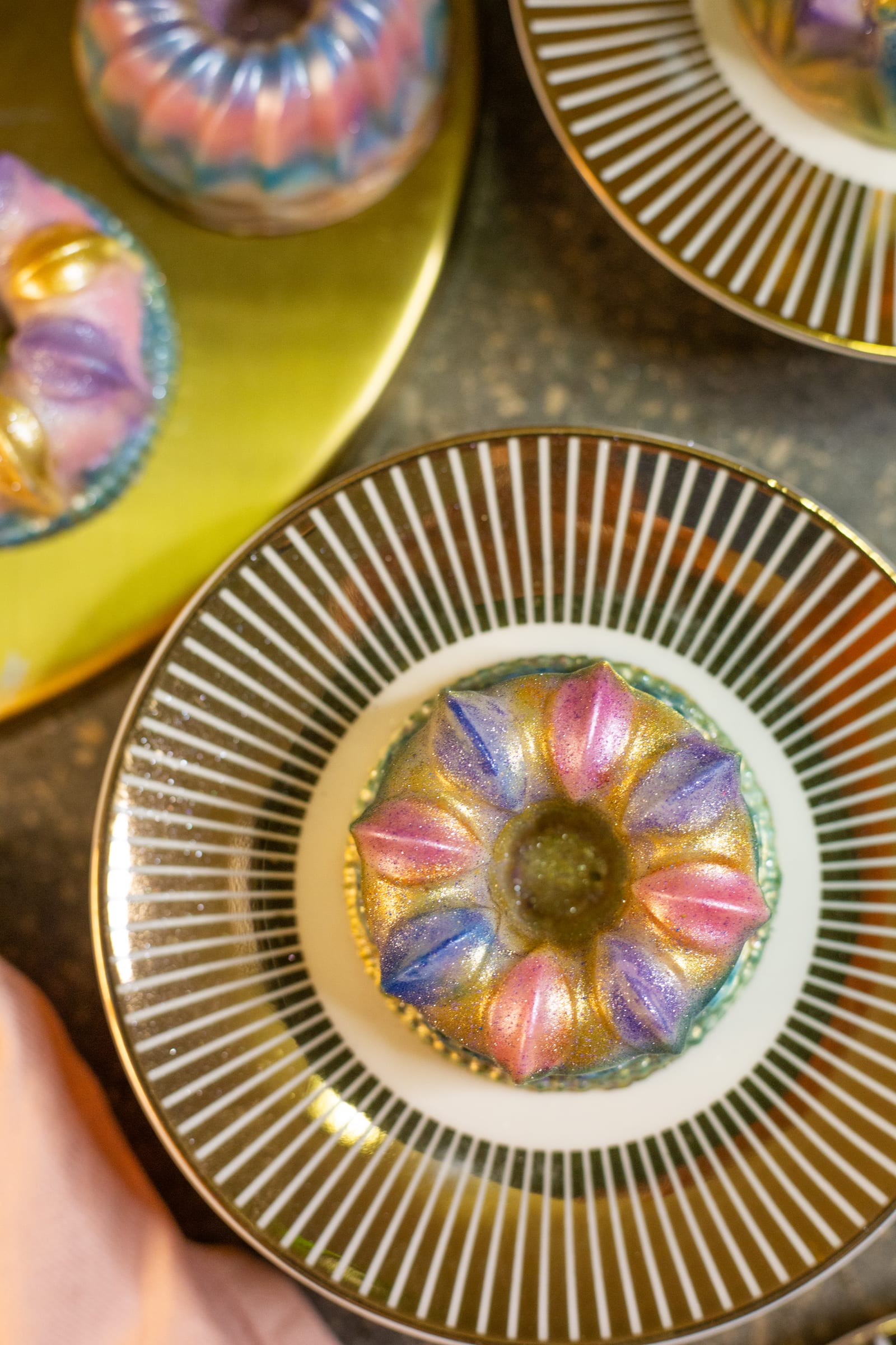 A painted Dubai pistachio burfee bundt on a striped gold plate, from above