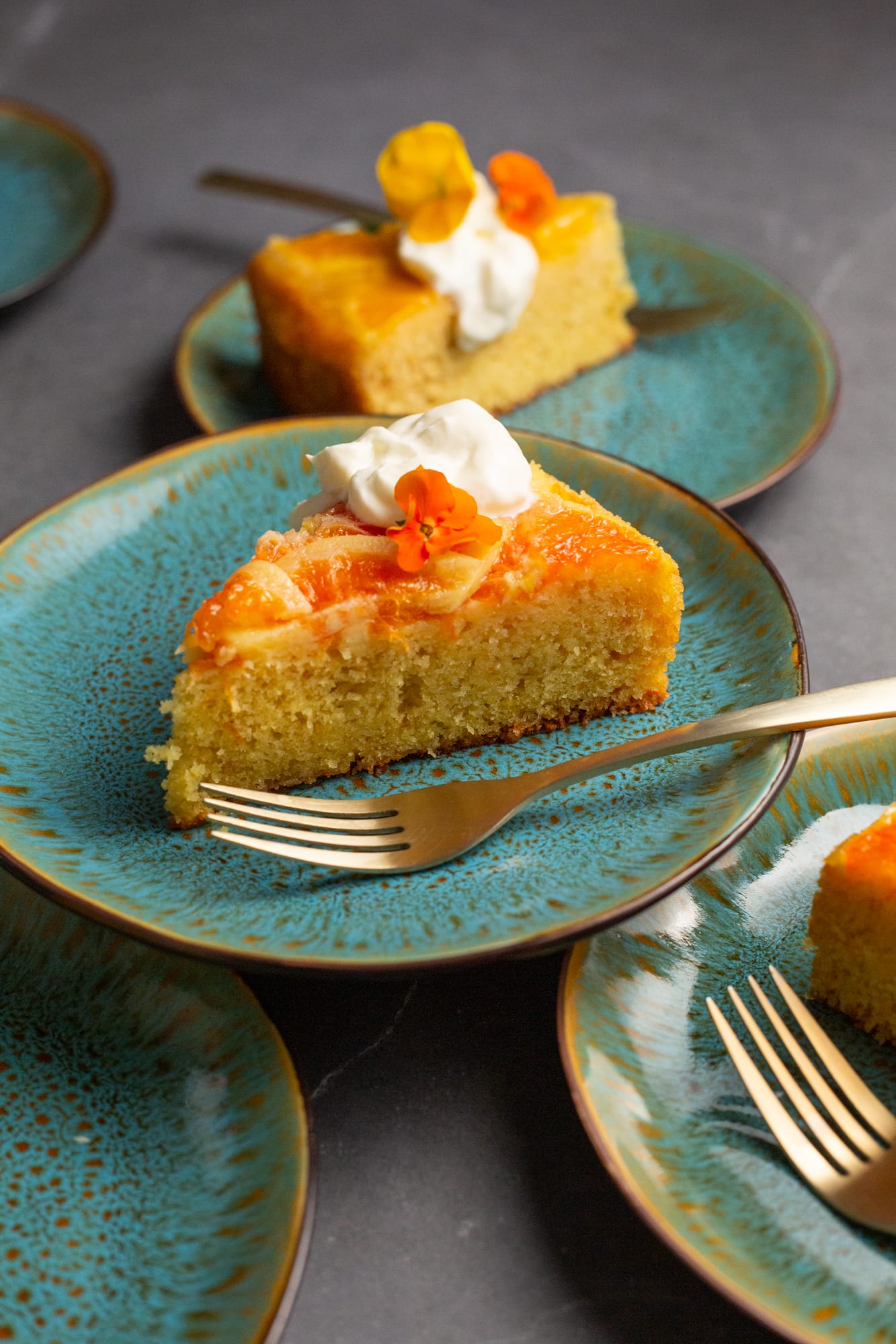 A slice of orange upside down cake with cream and a fork