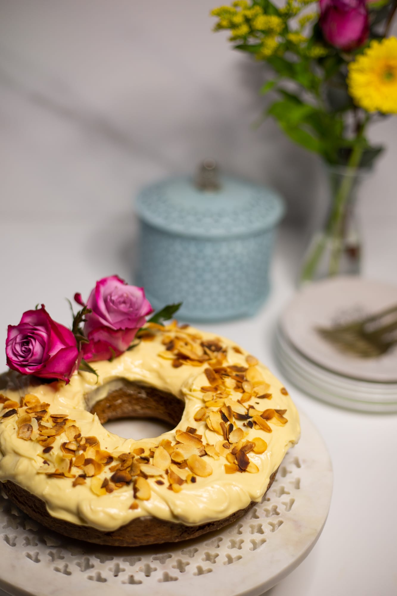 A citrus pound cake beside a pale blue tin, flowers and plates