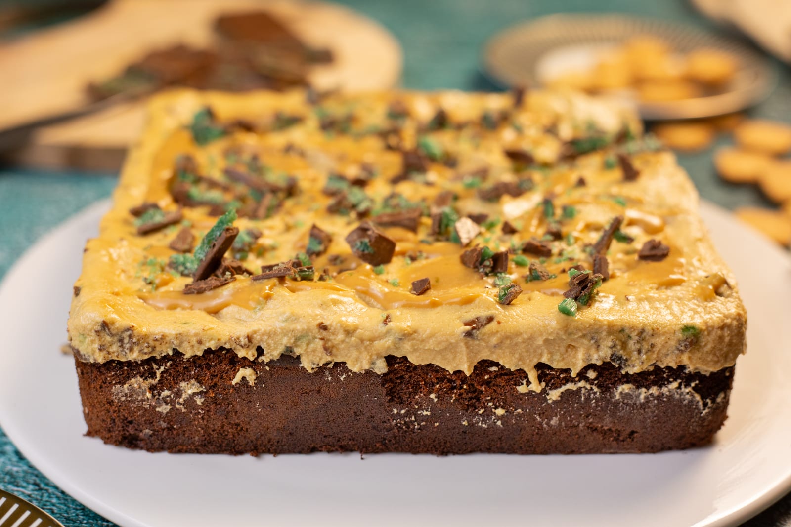 A peppermint crisp traybake with caramel frosting and grated peppermint crisp, on a white plate