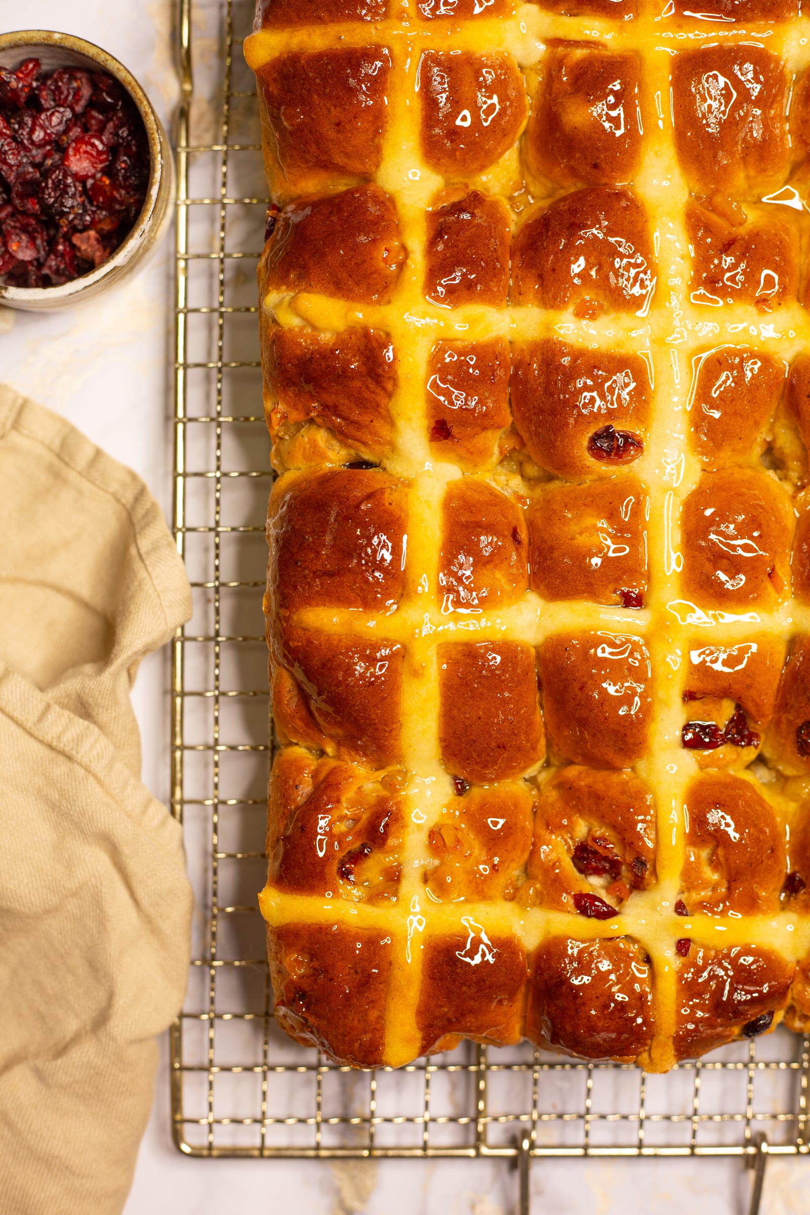 The tray of hot cross buns beside a bowl of dried cranberries