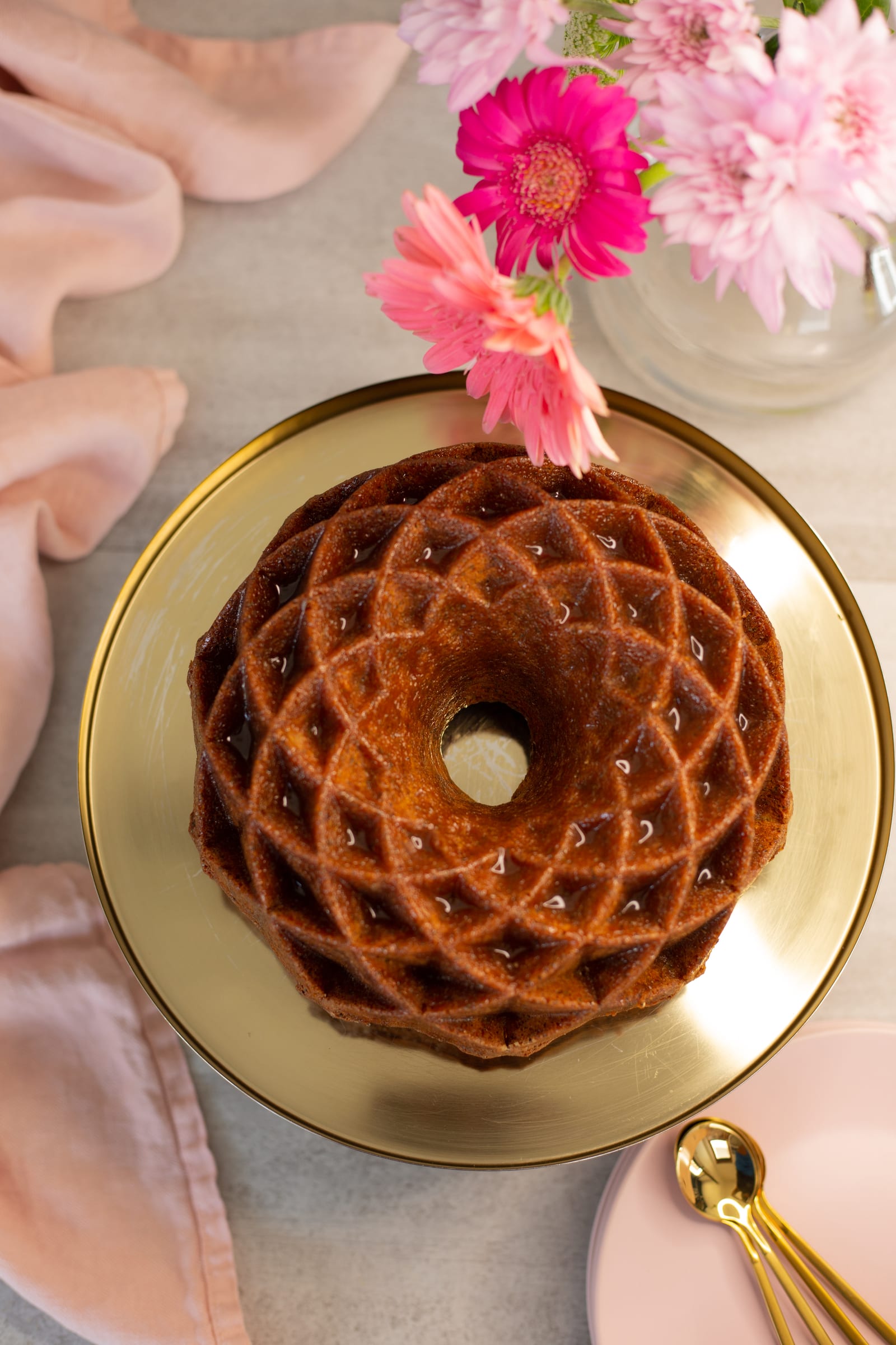 The lattice pattern of a lemon, poppyseed and olive oil bundt on a gold platter, from above