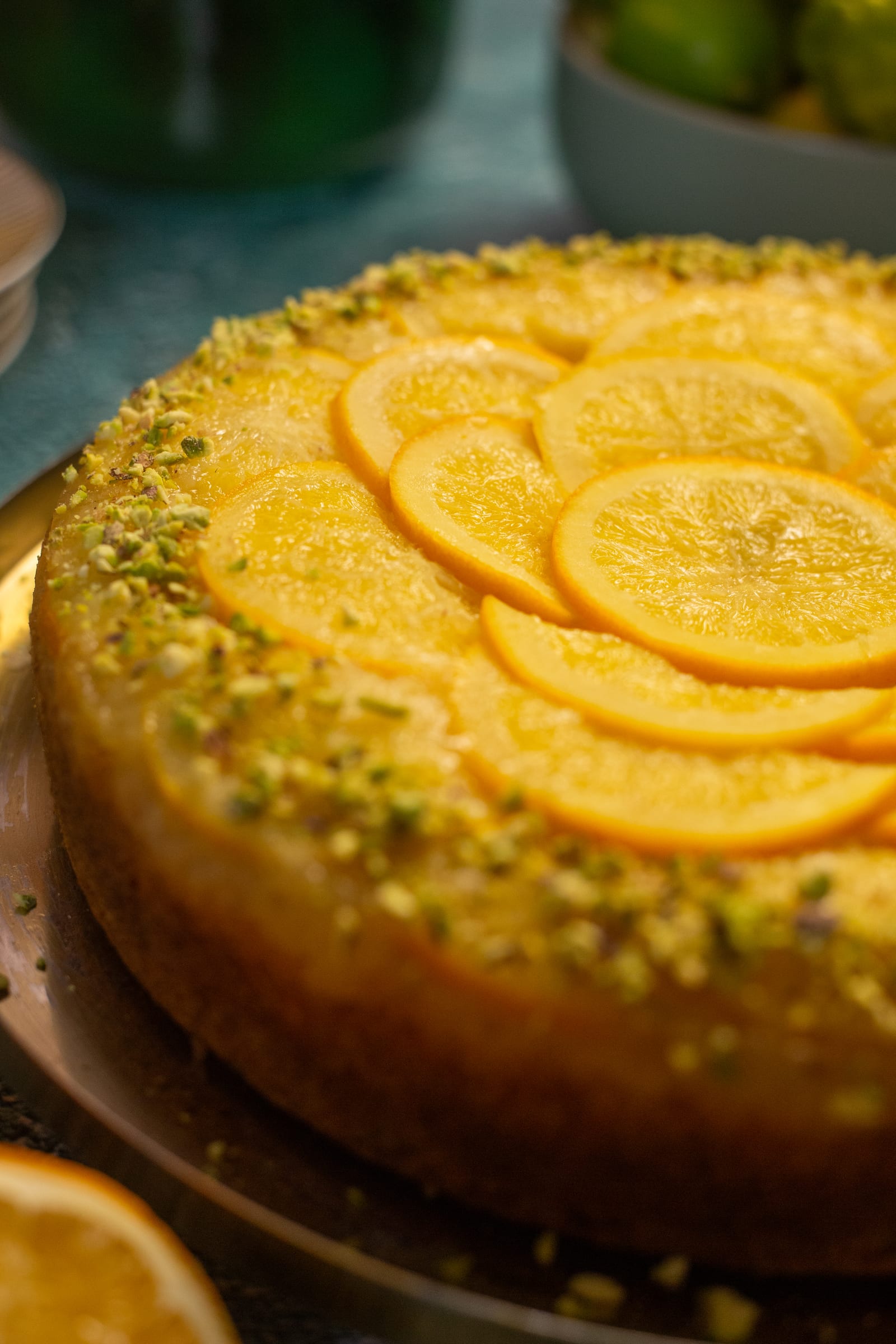 A close side view of the glossy orange slices and pistachio rim