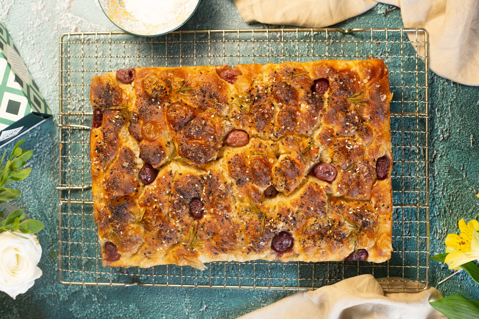 Rosemary and sea salt focaccia from above on a wire cooling rack, on a teal surface
