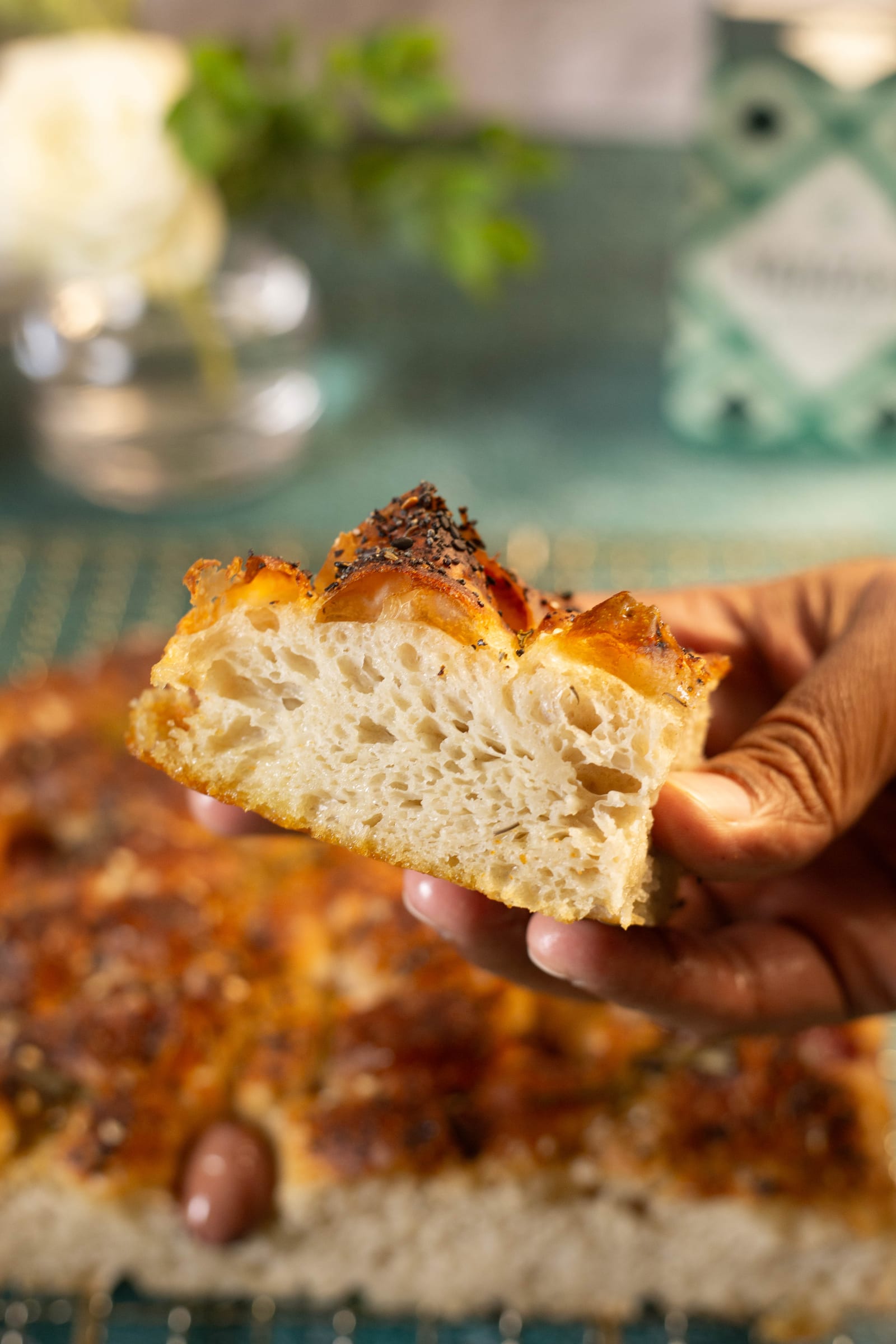 A hand holding a piece of focaccia