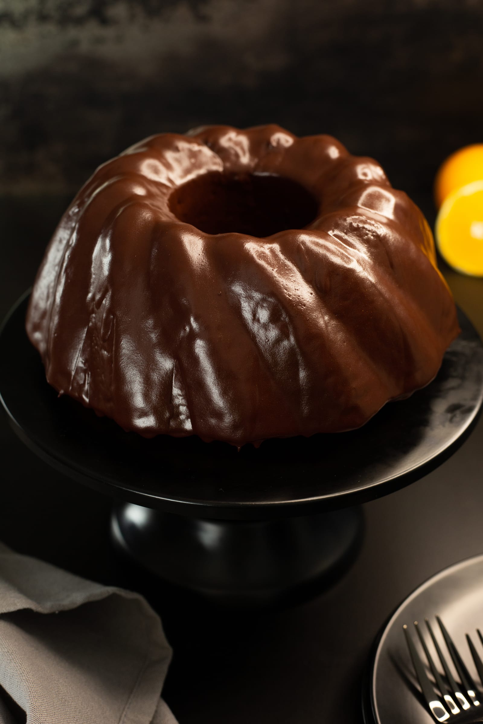 The ridges of the orange and olive oil bundt shining under its dark chocolate glaze