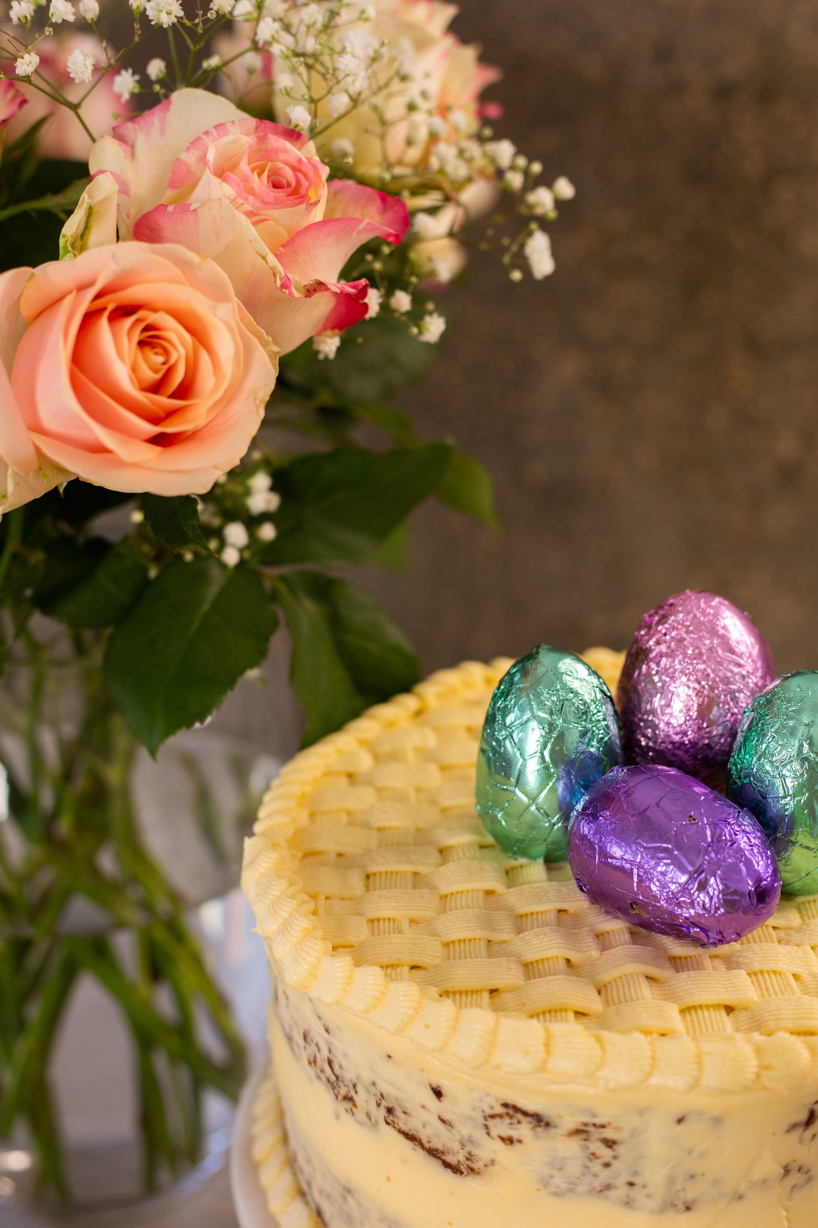 The basketweave gluten-free carrot cake with Easter eggs, roses behind