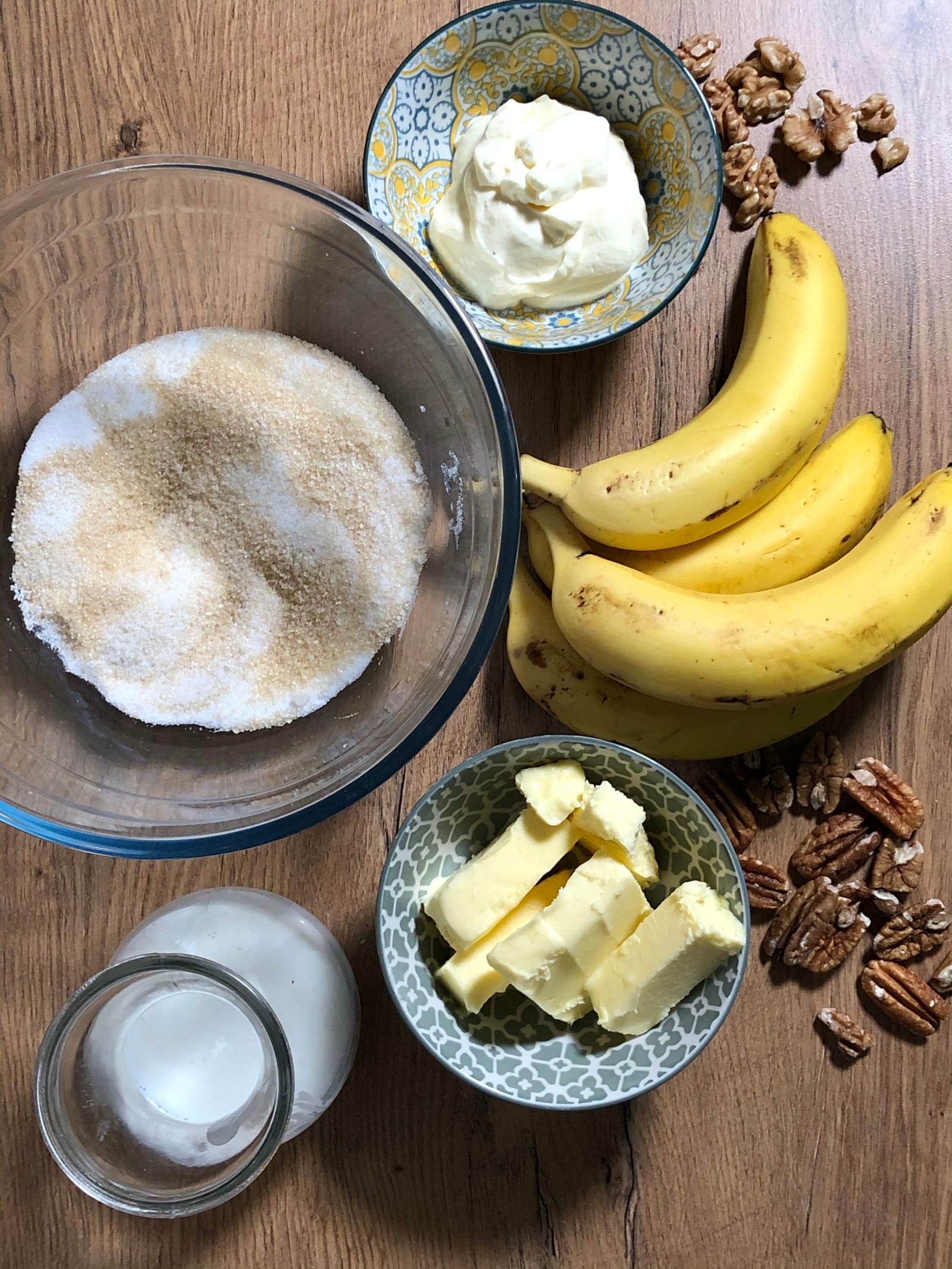 The ingredients for banana and pecan nut bread on a wooden table, from above