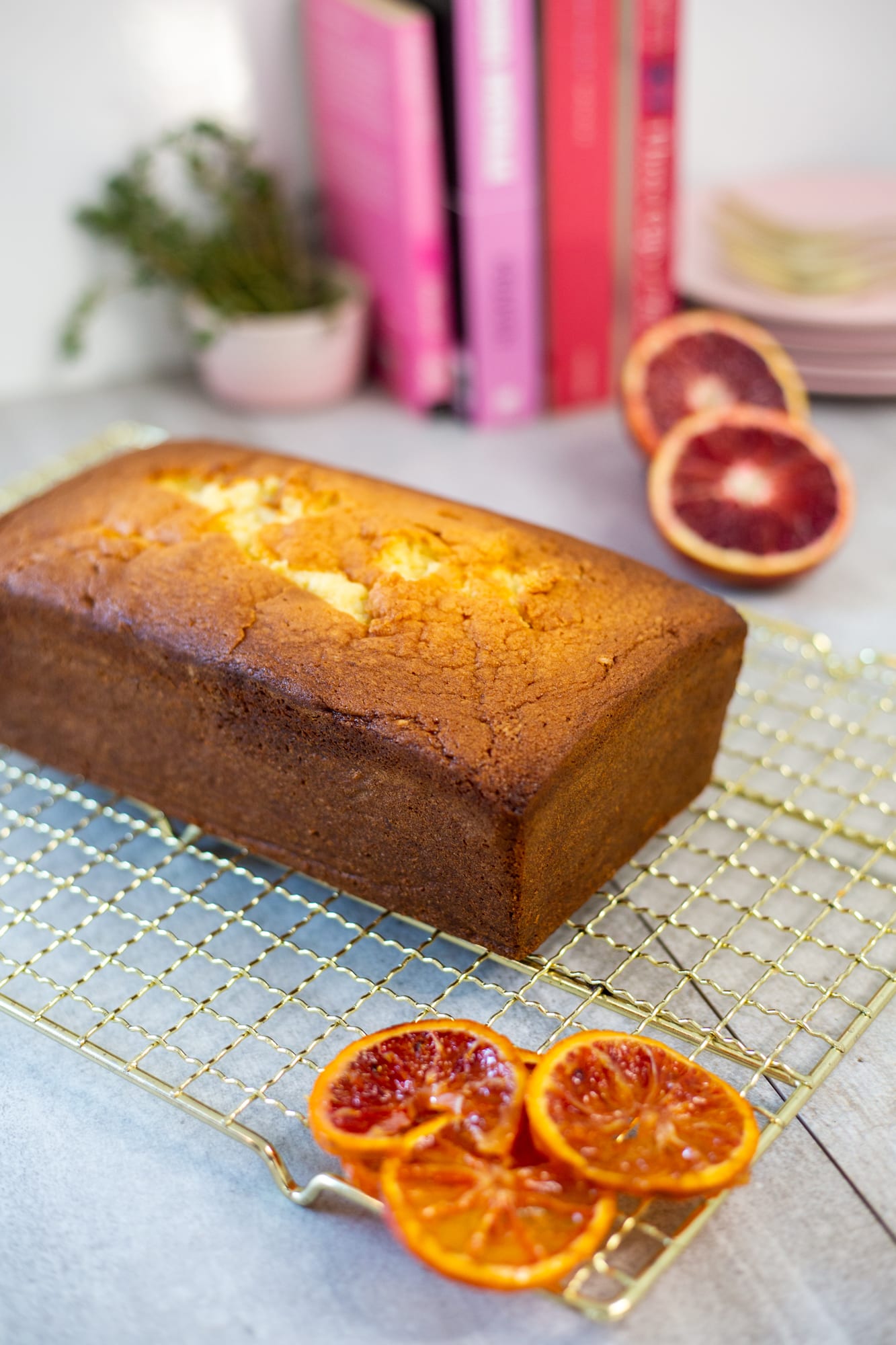 A plain cream cheese pound cake on a gold wire rack before glazing