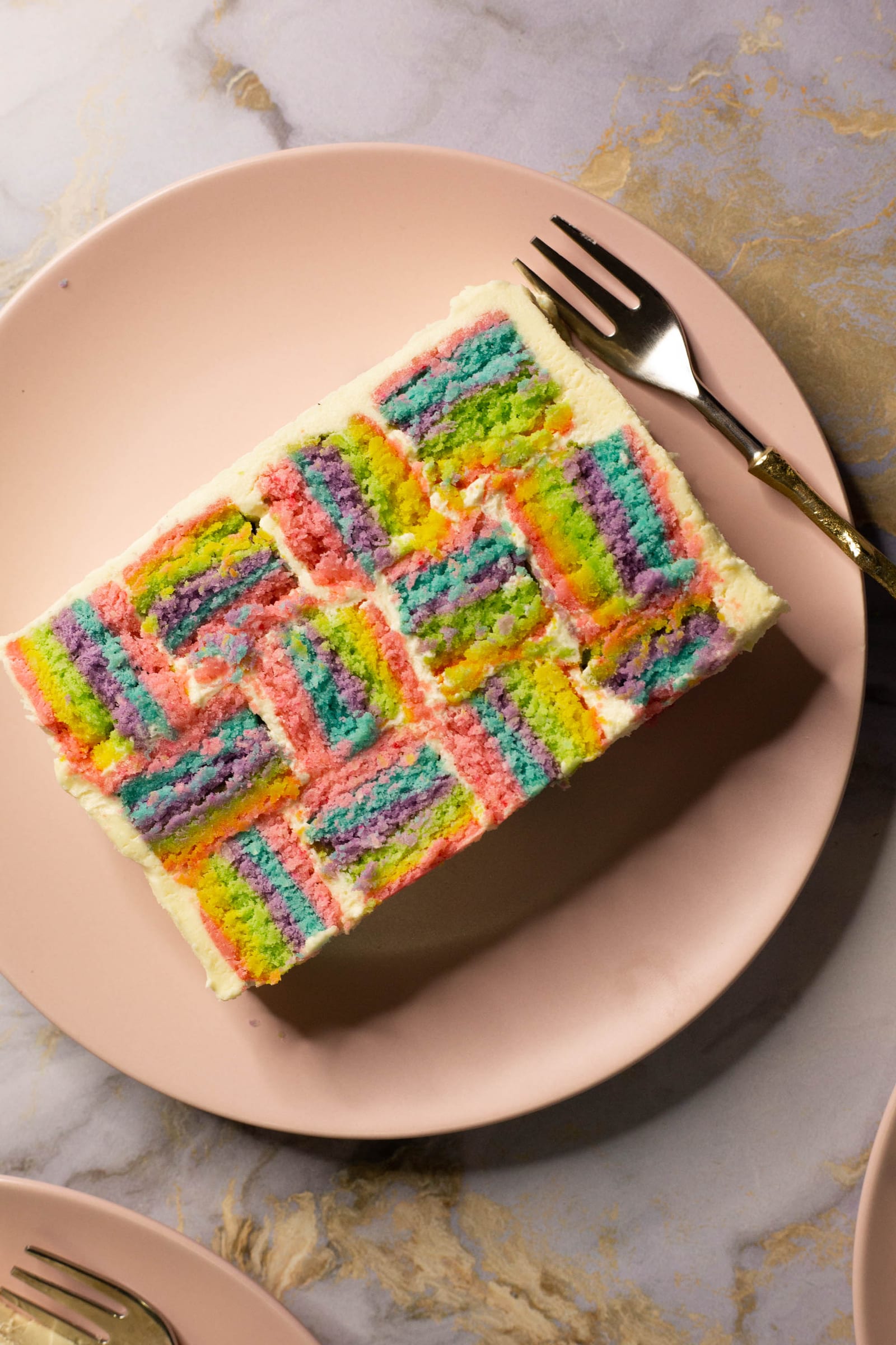 A slice of rainbow coconut layer cake on a pink plate, from above