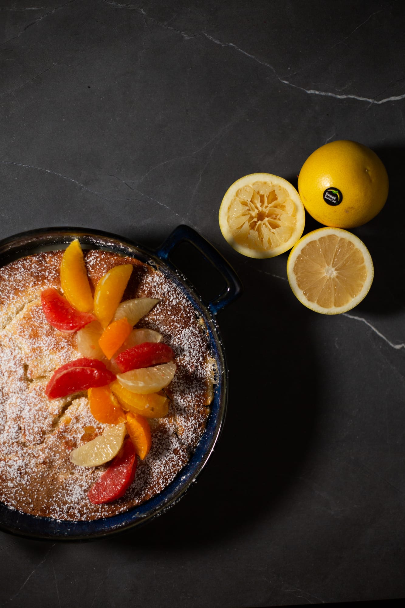 The citrus pudding topped with grapefruit and orange slices, beside lemons