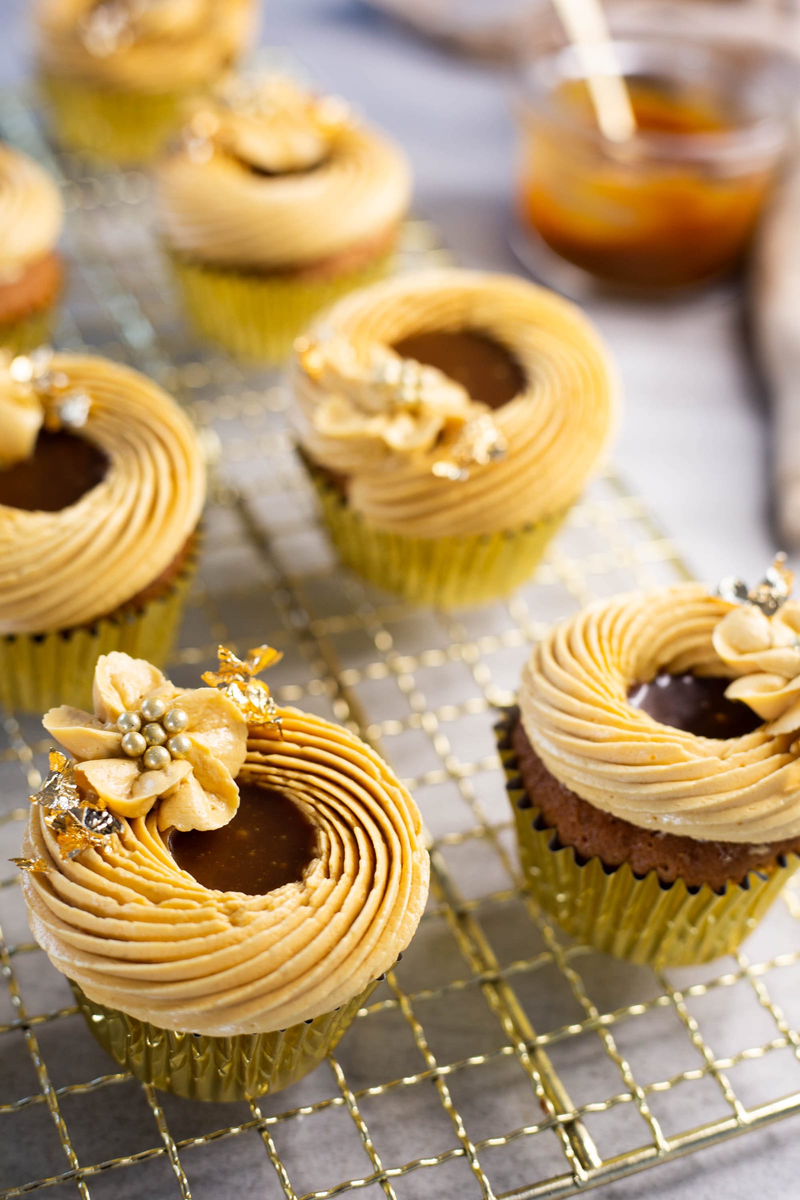 The piped caramel buttercream swirl and gold sugar flower on top of a salted caramel cupcake
