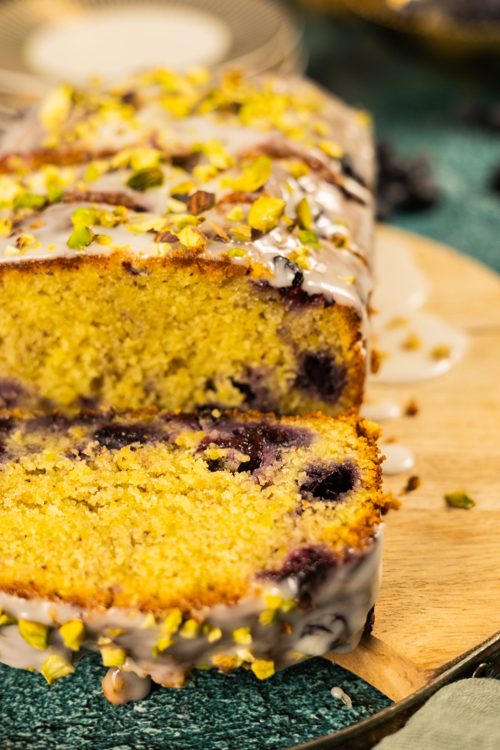 Slices of pistachio, blueberry and lime loaf, showing the blueberries in the crumb