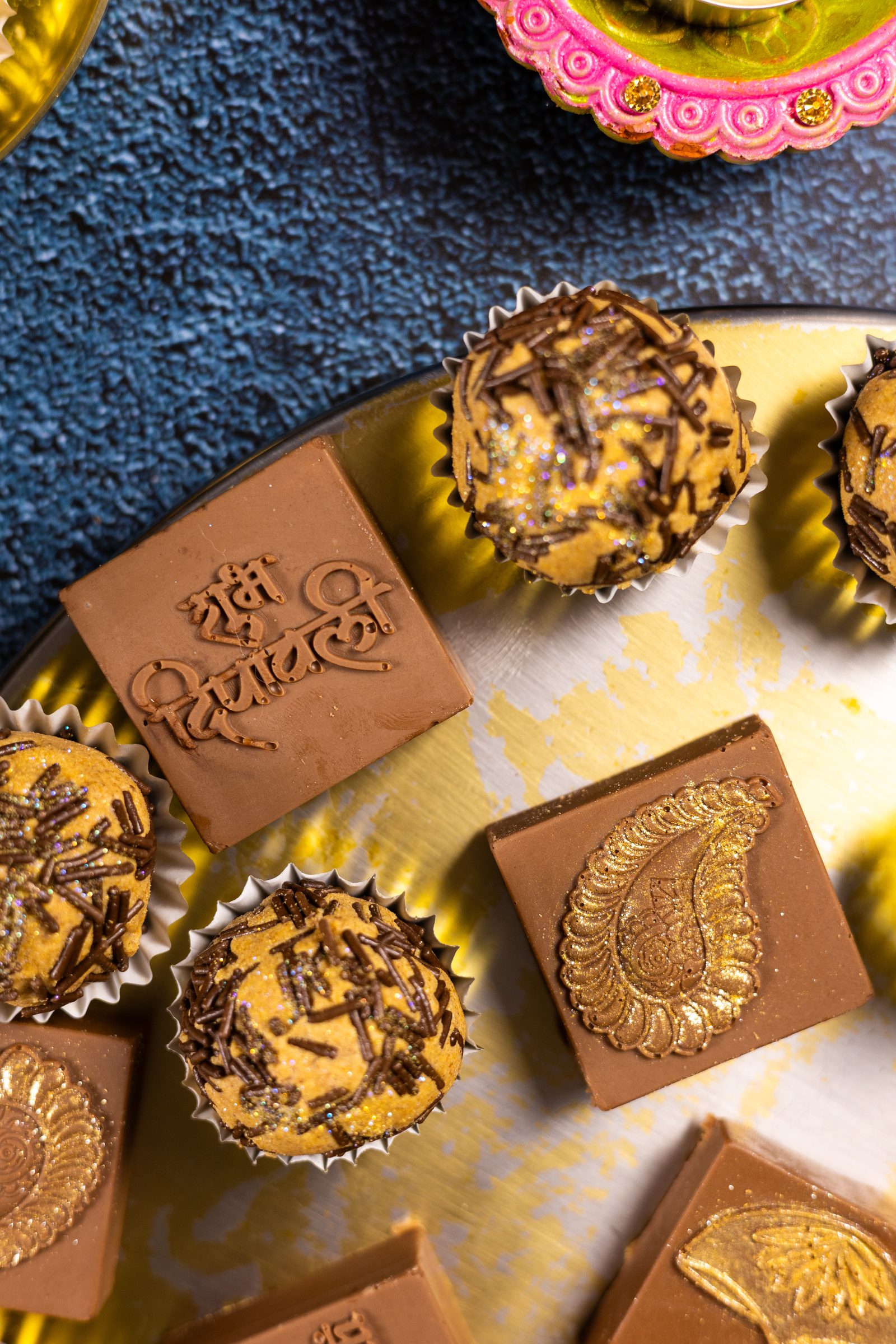 Caramel and chocolate Simply Wonderfuls on a gold platter from above, one stamped with a Diwali greeting in Hindi