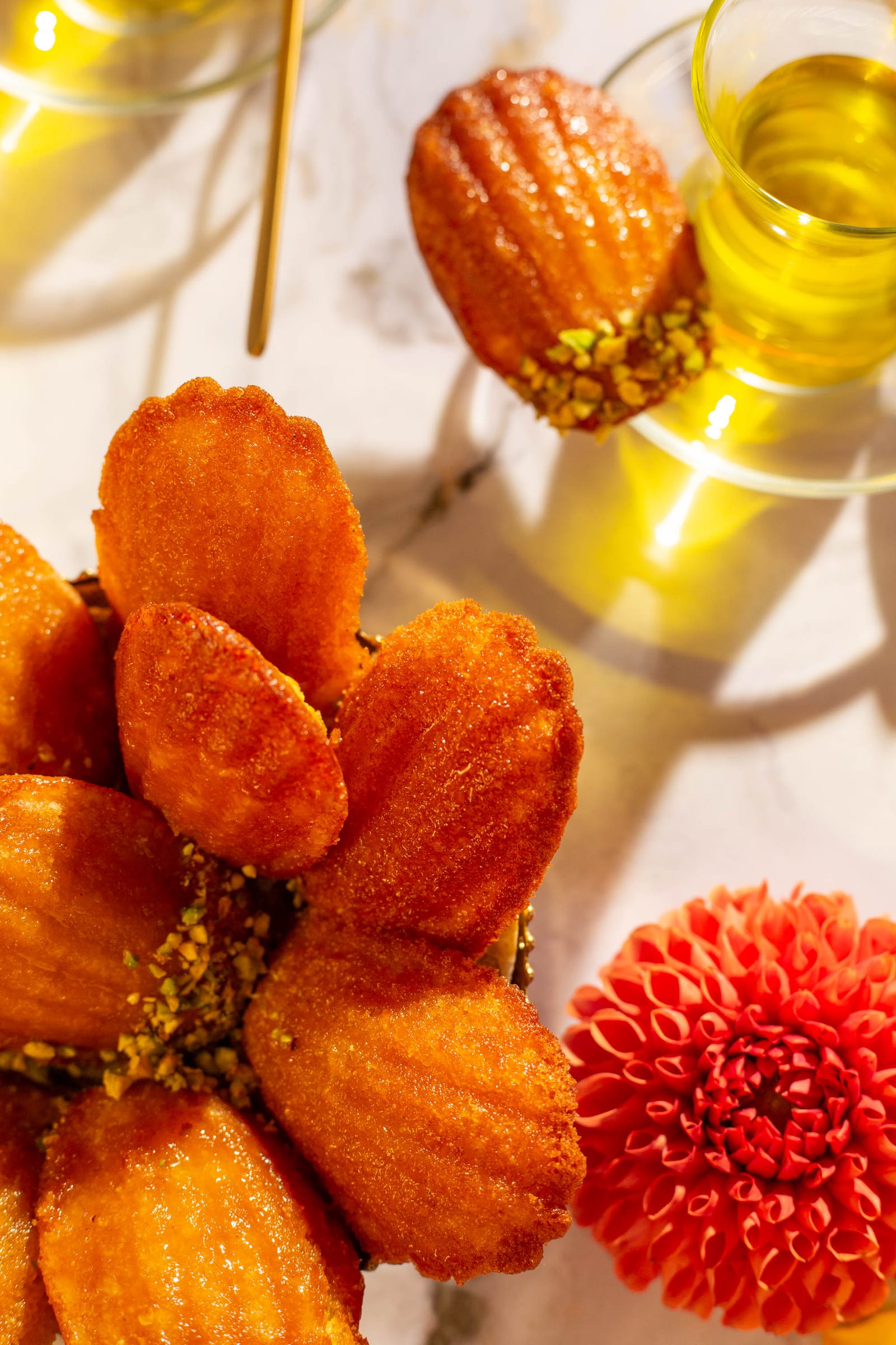 Close-up of the madeleine flower with its crushed pistachio centre and a red dahlia