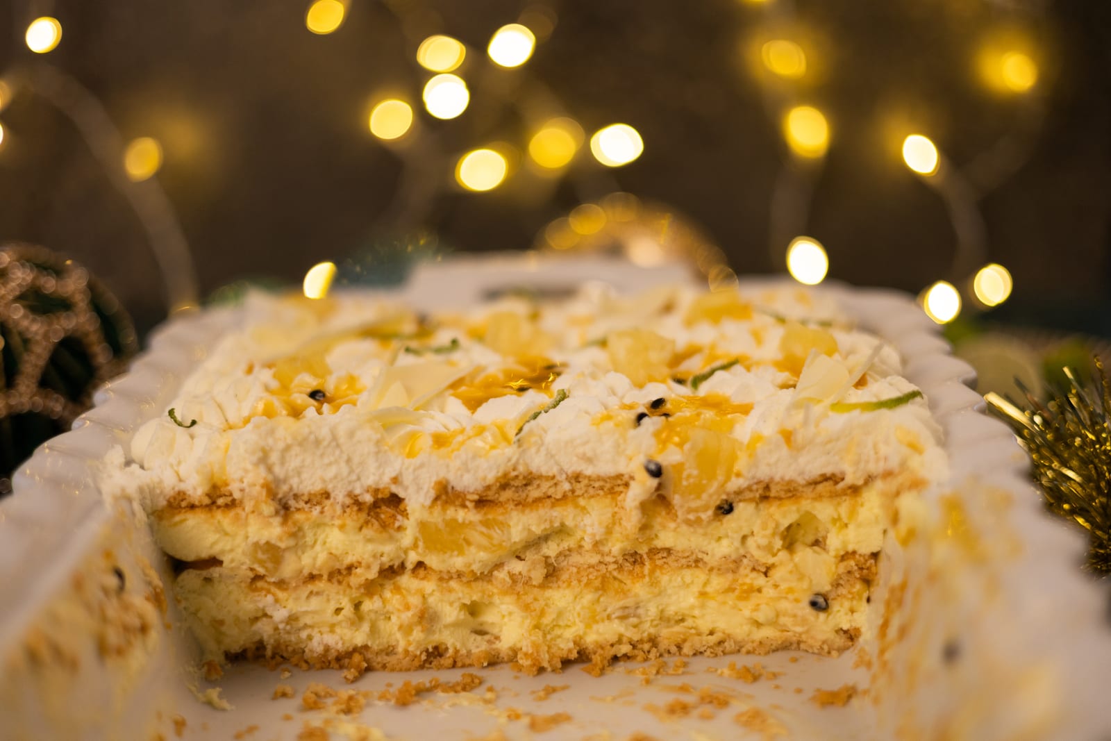 A pineapple fridge tart cut open to show its layers, with fairy lights behind