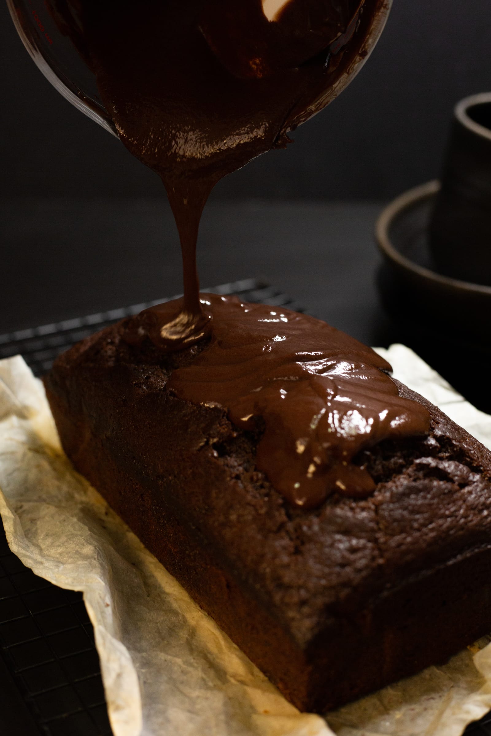 Chocolate ganache being poured over the top of the chocolate banana bread