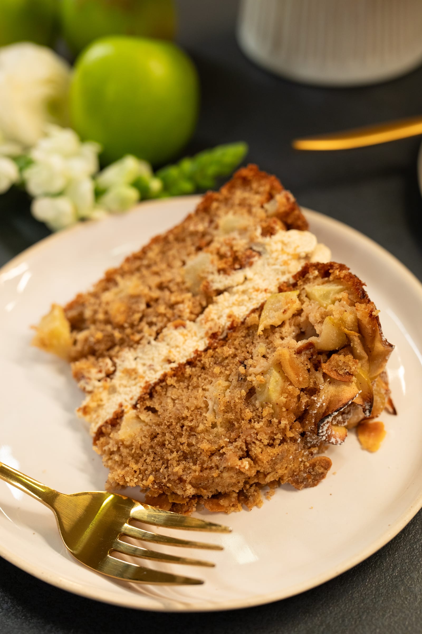 A slice of apple crumble cake showing the apple-studded crumb and maple cream cheese icing