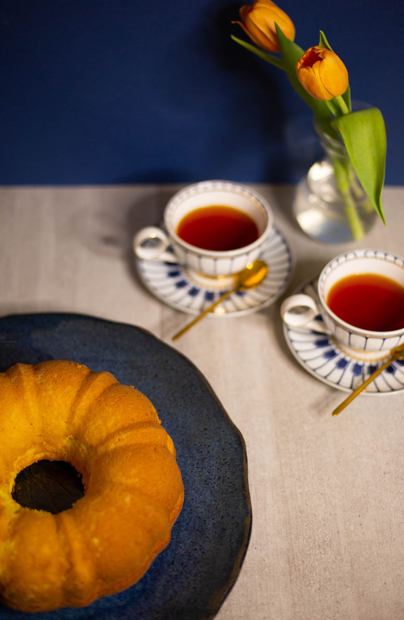 An unglazed saffron milk cake beside teacups, from slightly above