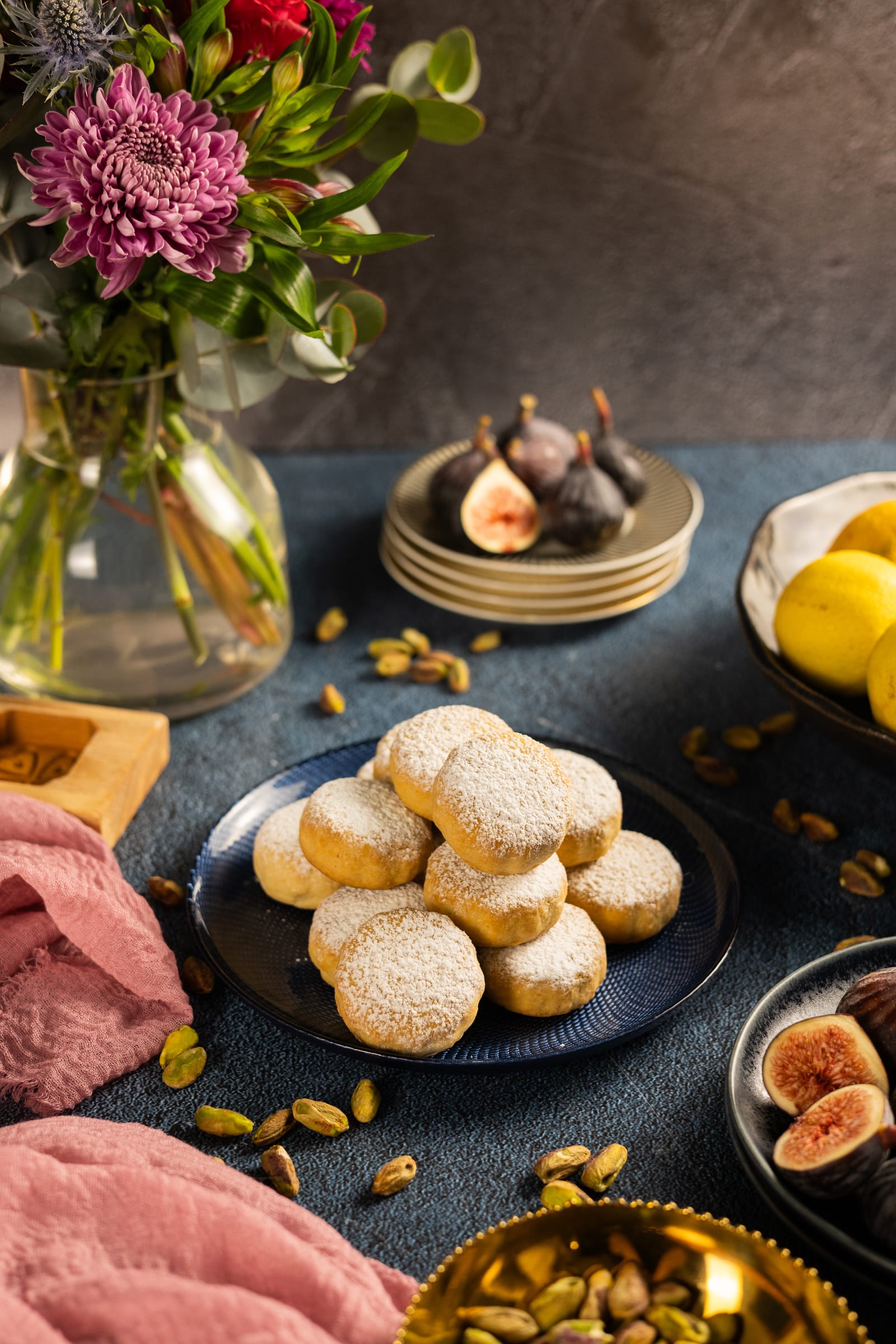 A plate of ma'amoul with flowers, figs and lemons behind