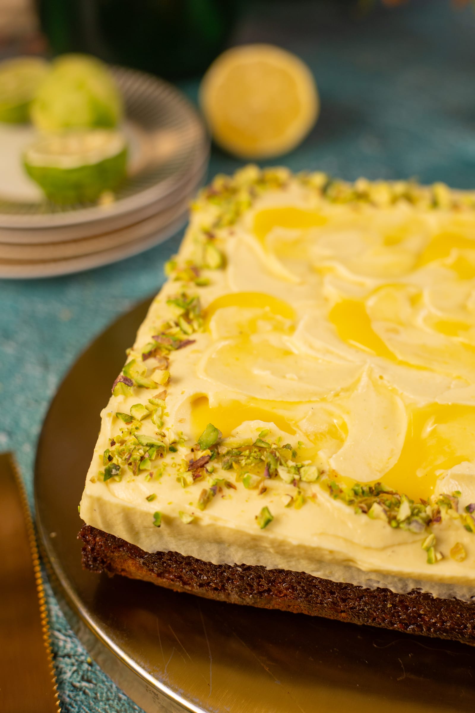 The pistachio and lemon traybake from the side, showing the golden sponge under the whipped lemon custard