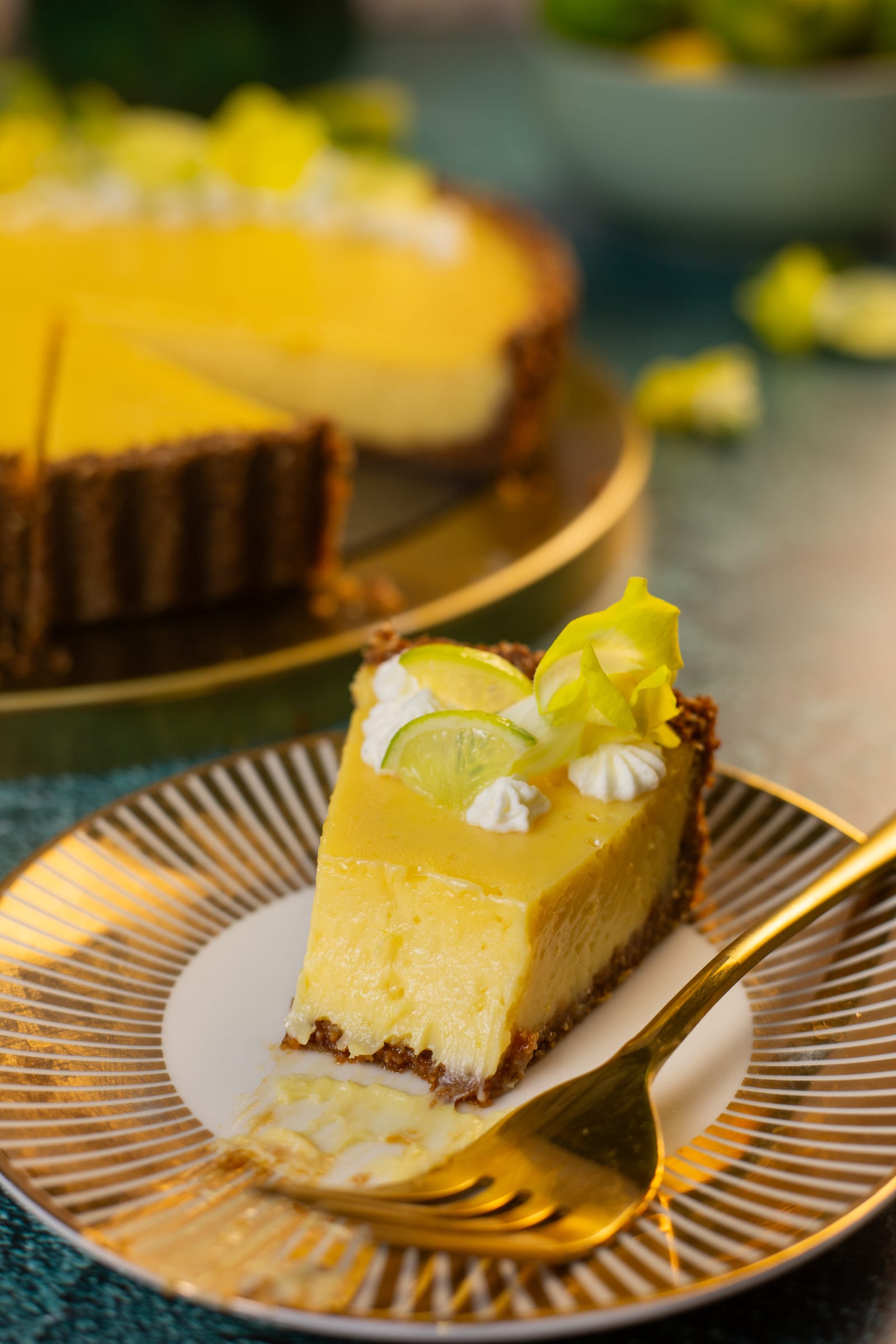 A slice of key lime pie on a gold plate with a fork
