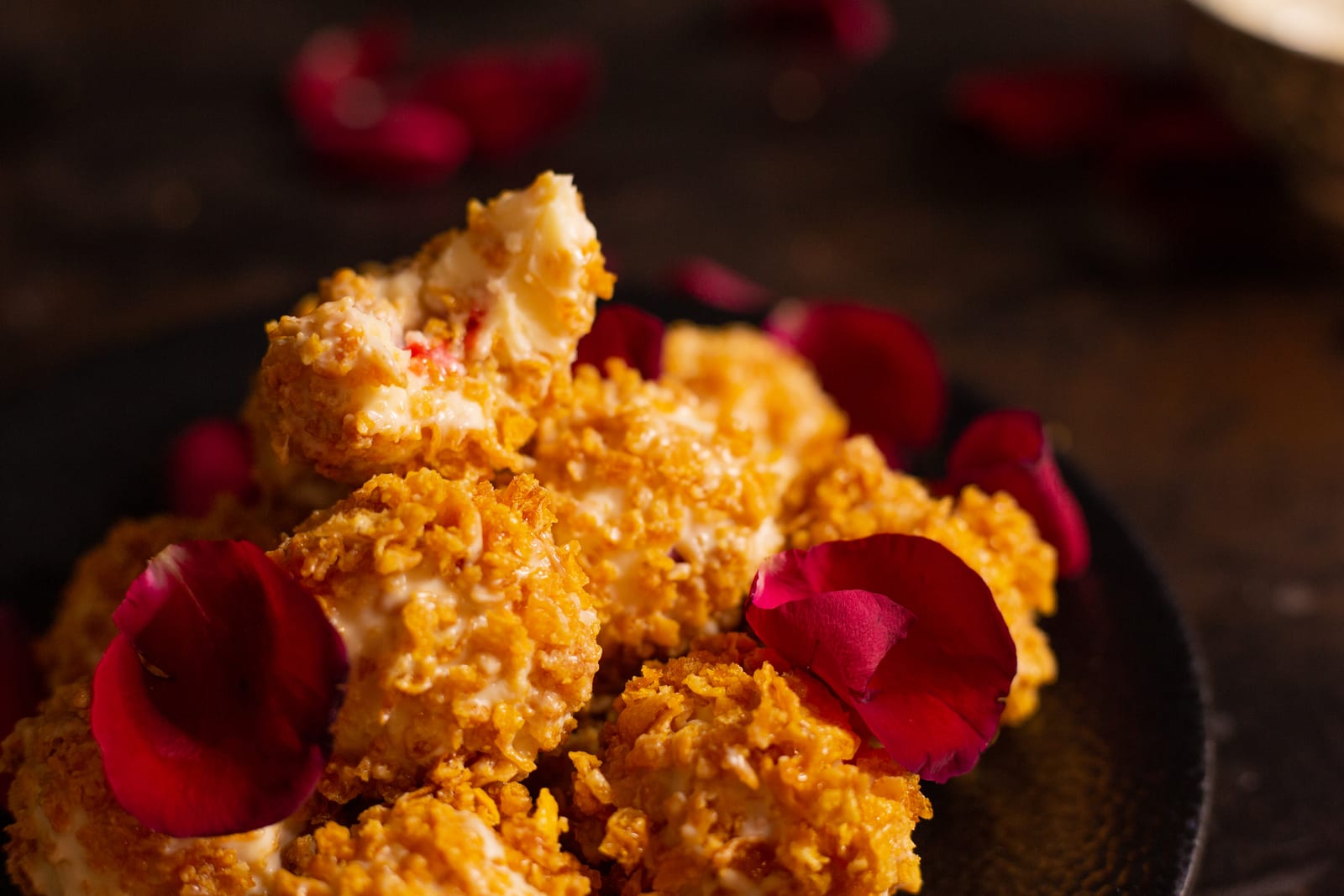 Raspberry and white chocolate truffles piled with rose petals, a few halved to show their pink raspberry centres