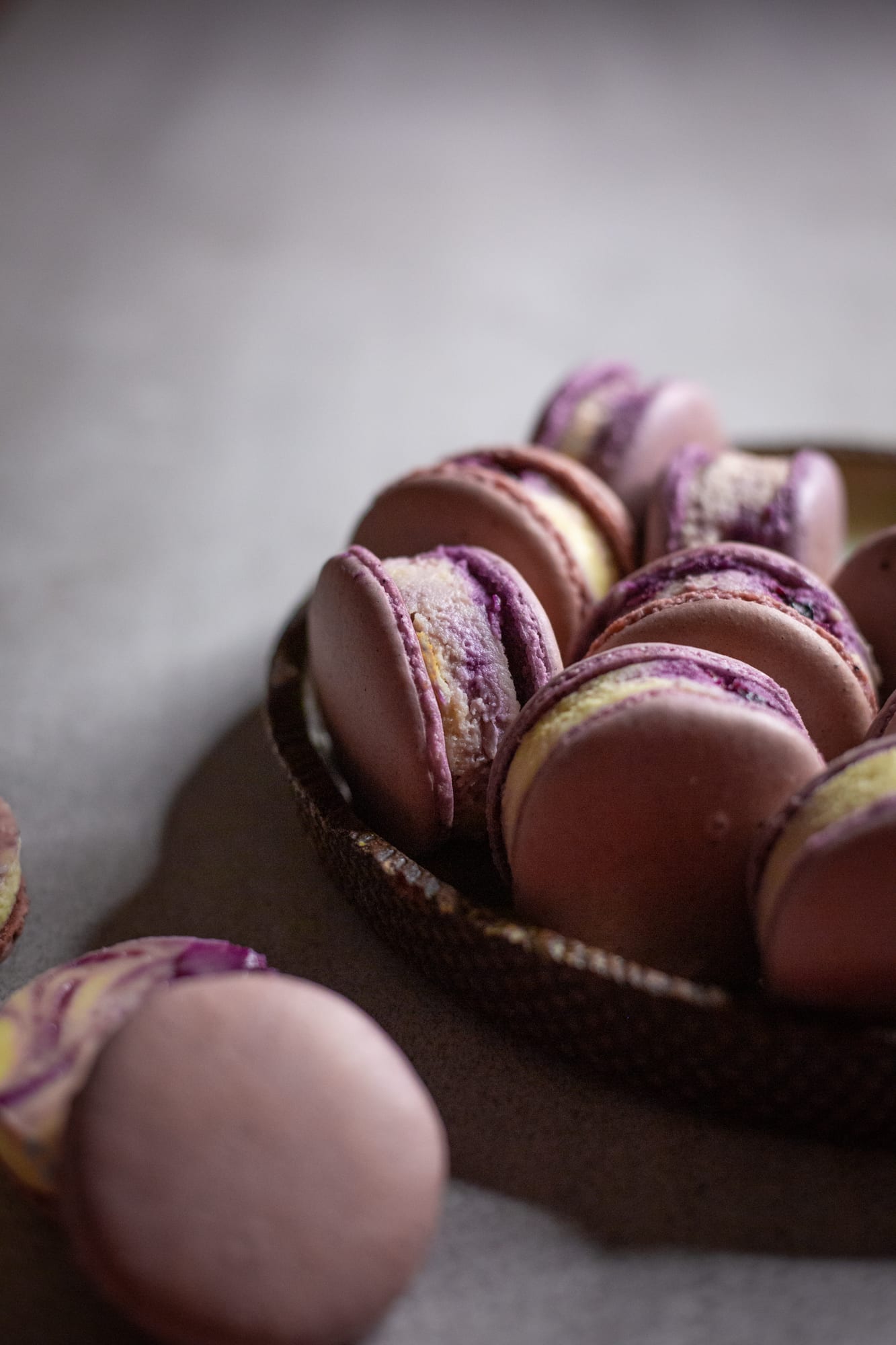 A plate of blueberry cheesecake macarons behind a blurred macaron in the foreground