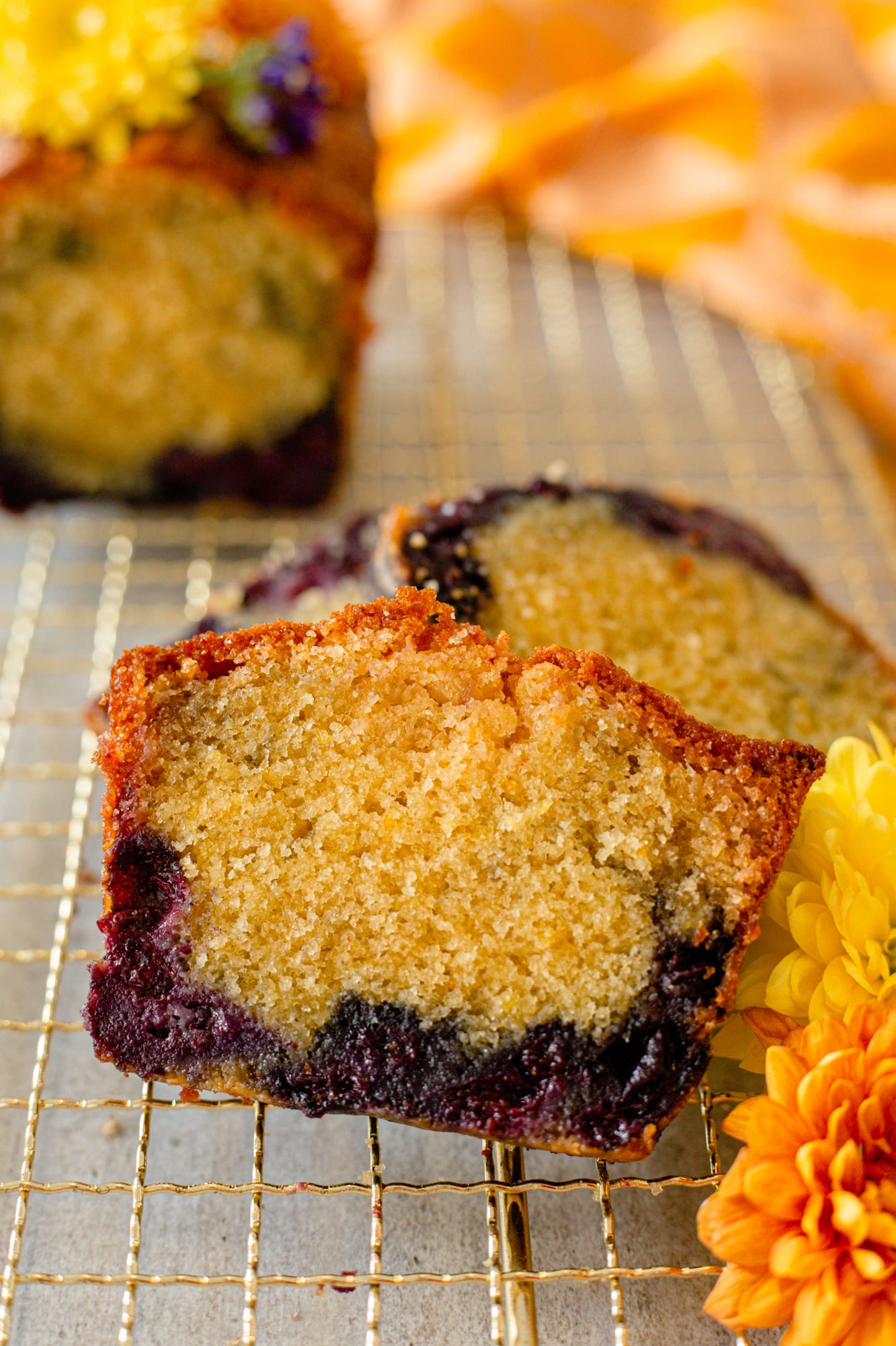 Two cut ends of a lemon and blueberry loaf showing the crumb, with flowers