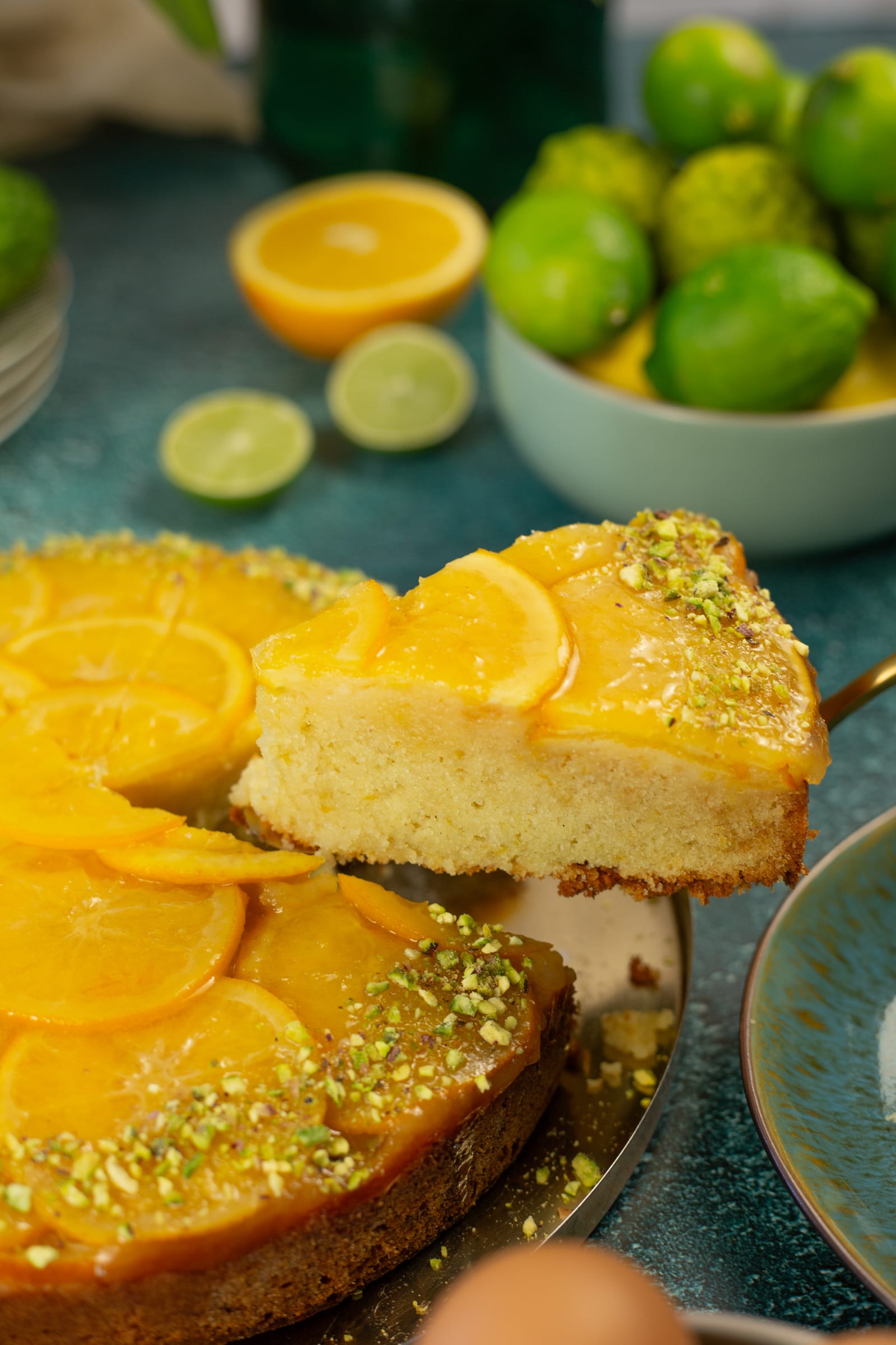 A slice of orange and olive oil upside down cake being lifted out, showing the soft crumb