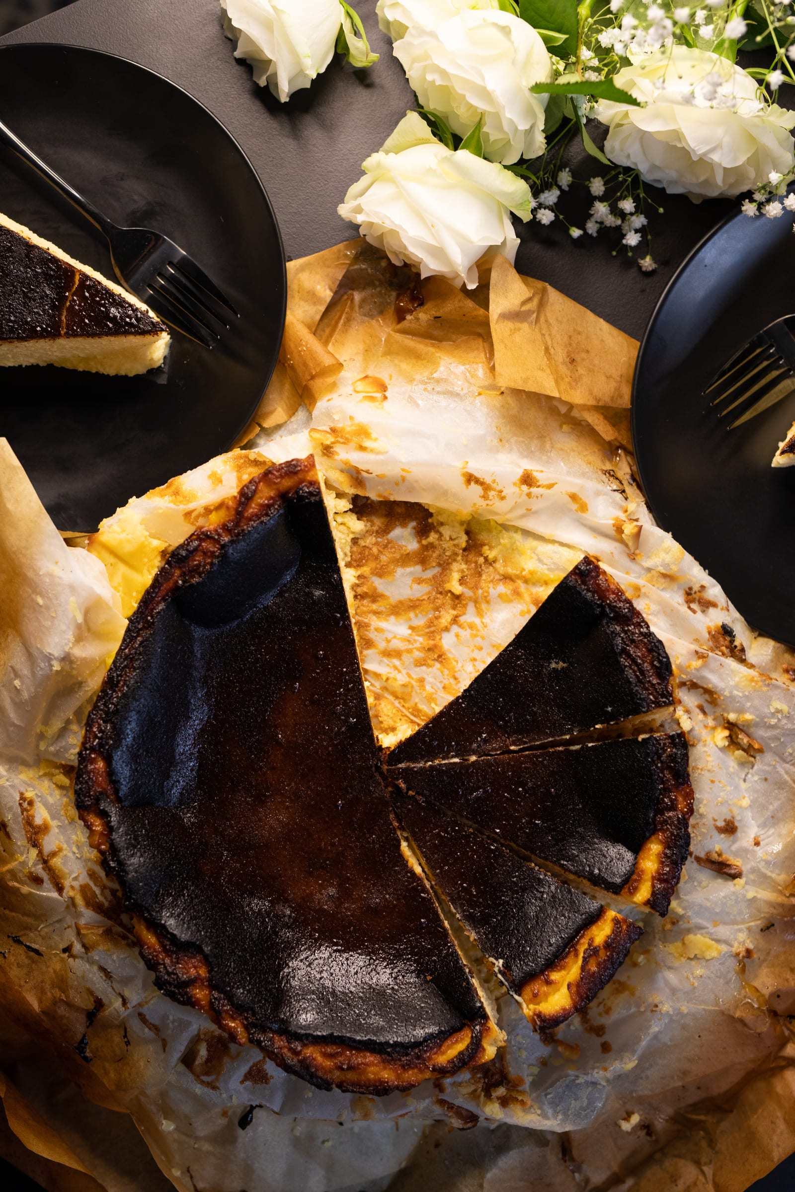 A cut Basque cheesecake from above, with slices taken out and plated around it