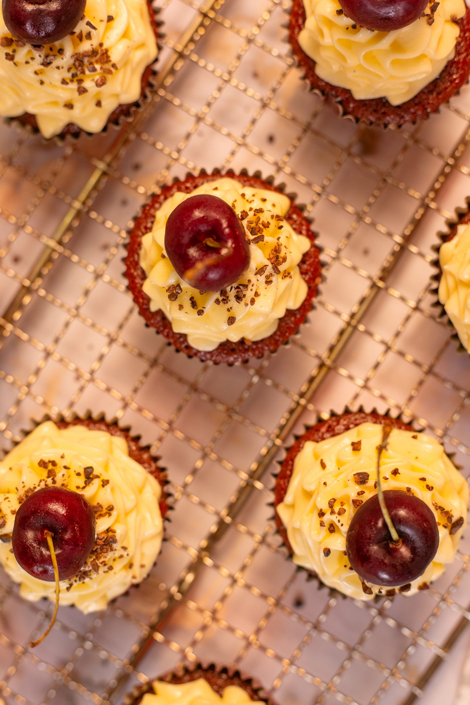 Frosted cupcakes with cherries and chocolate shavings, from above
