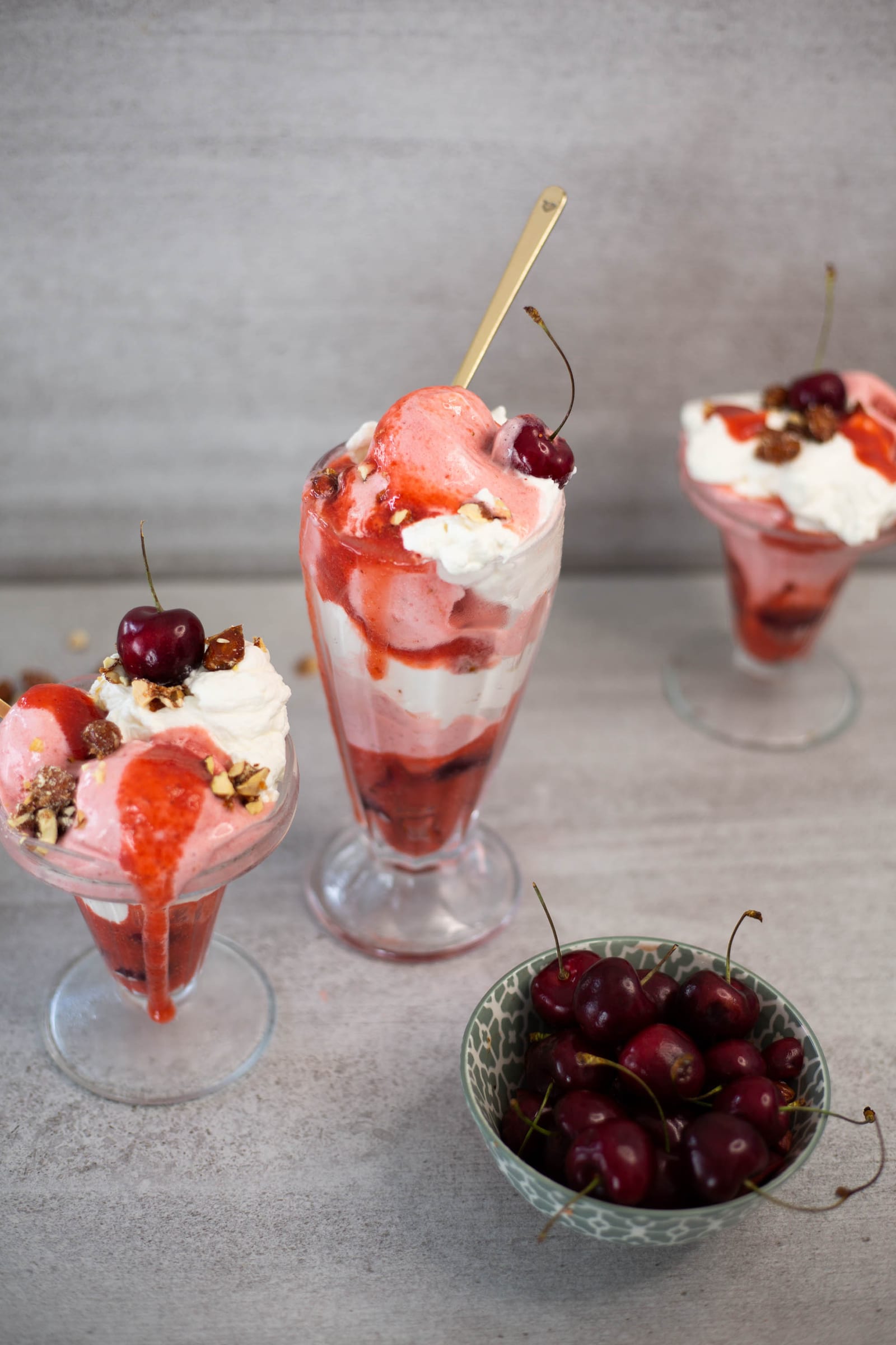 Three berries and cream sundaes from above with a bowl of fresh cherries