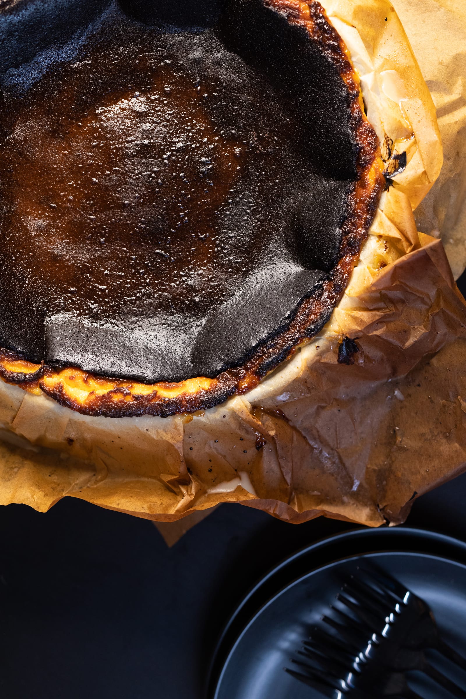 The cracked, deeply caramelised top of a Basque cheesecake and its paper edge, from above