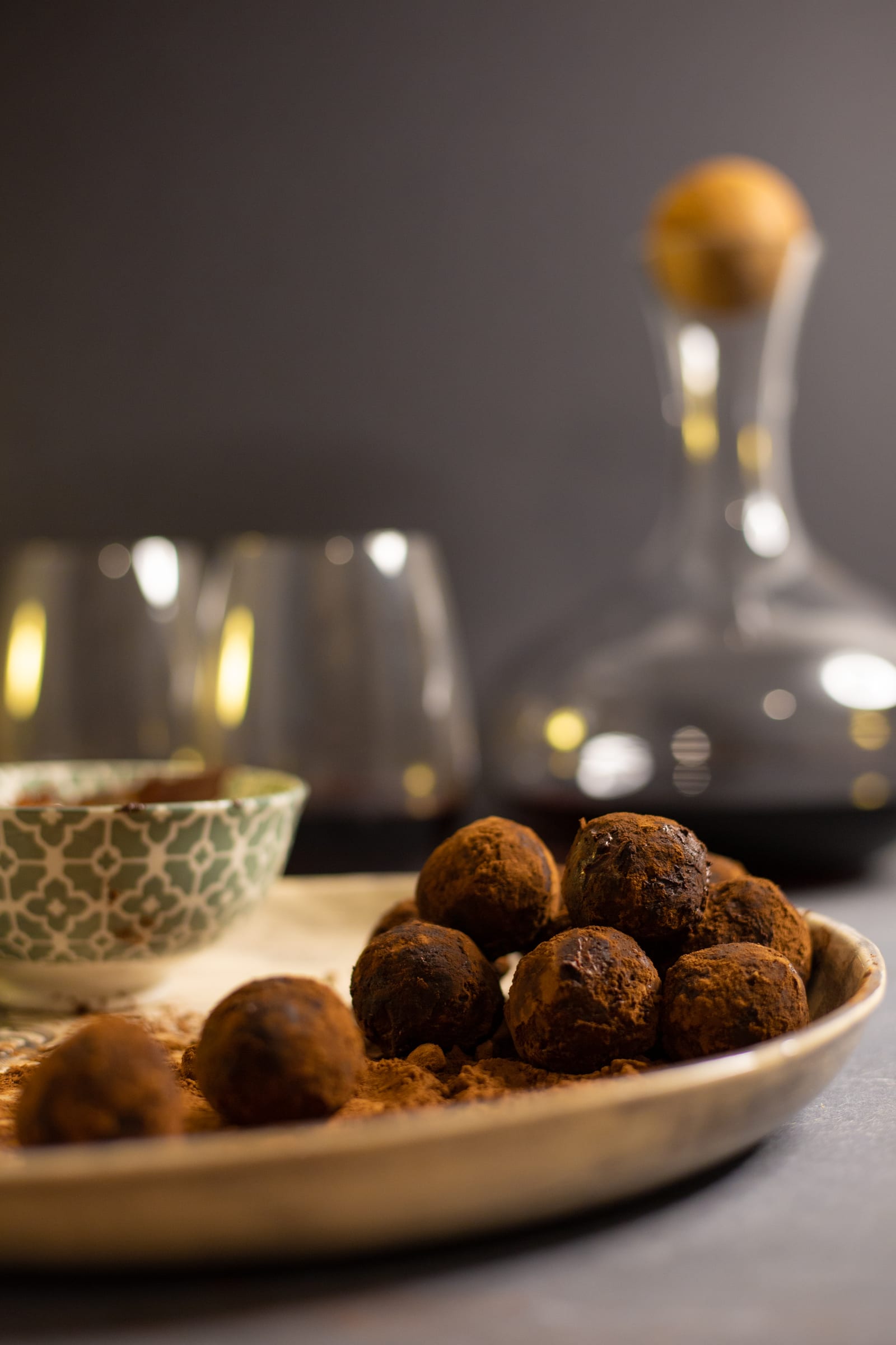 A pile of rum and raisin truffles with a decanter and glasses behind