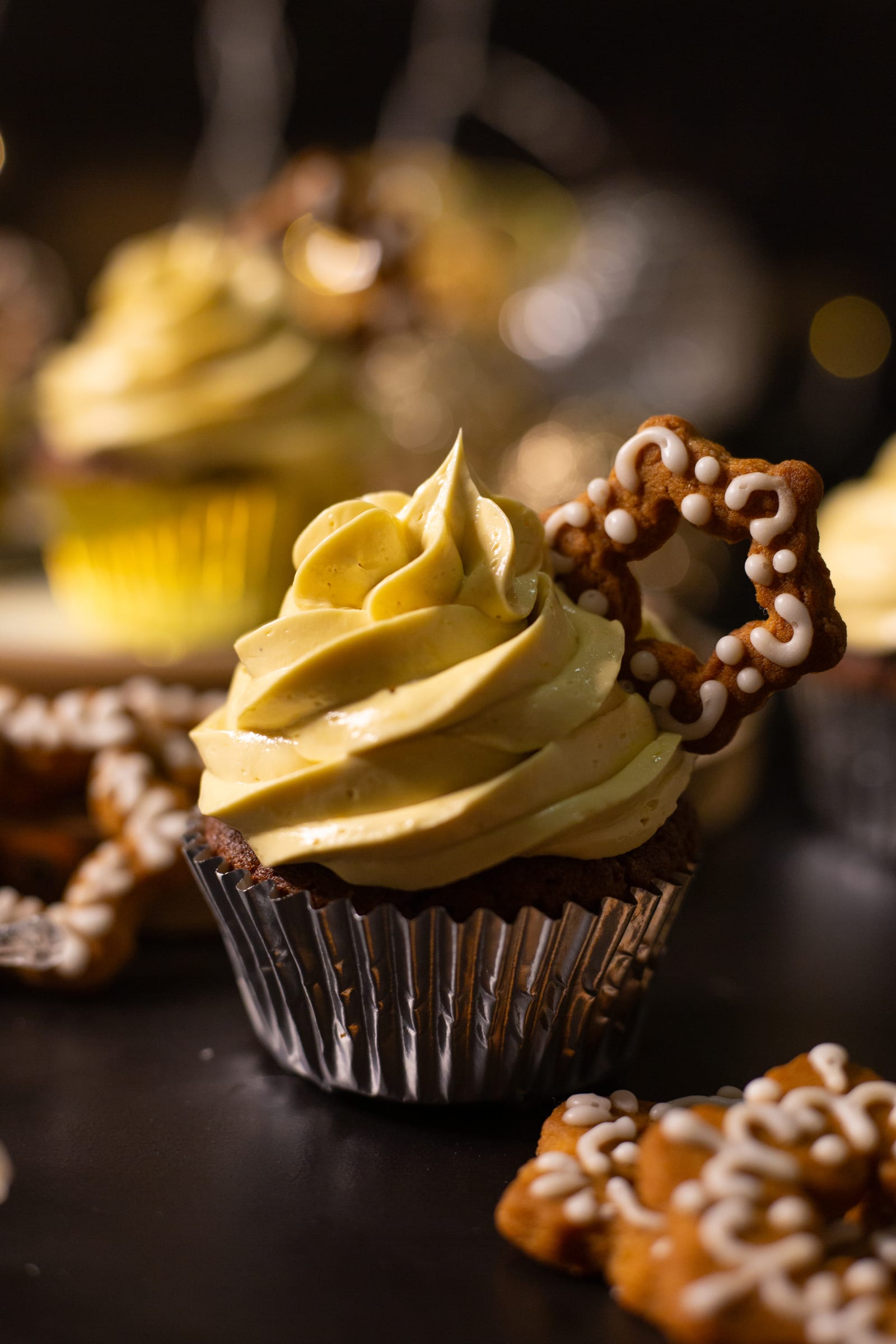 A gingerbread cupcake in a silver case, crowned with eggnog buttercream and a pretzel star