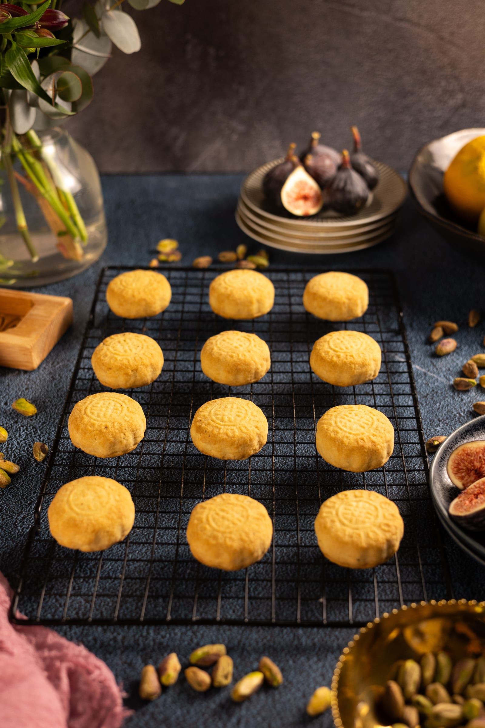 Rows of baked ma'amoul on a wire rack, with figs and flowers