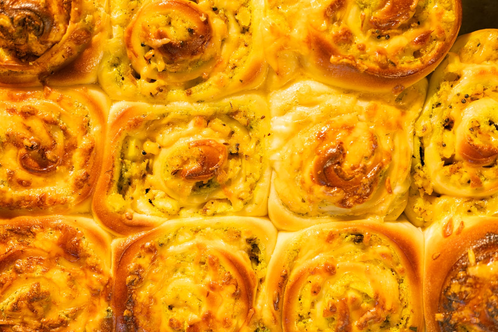 Golden baked jeera aaloo scrolls packed in a tray, up close