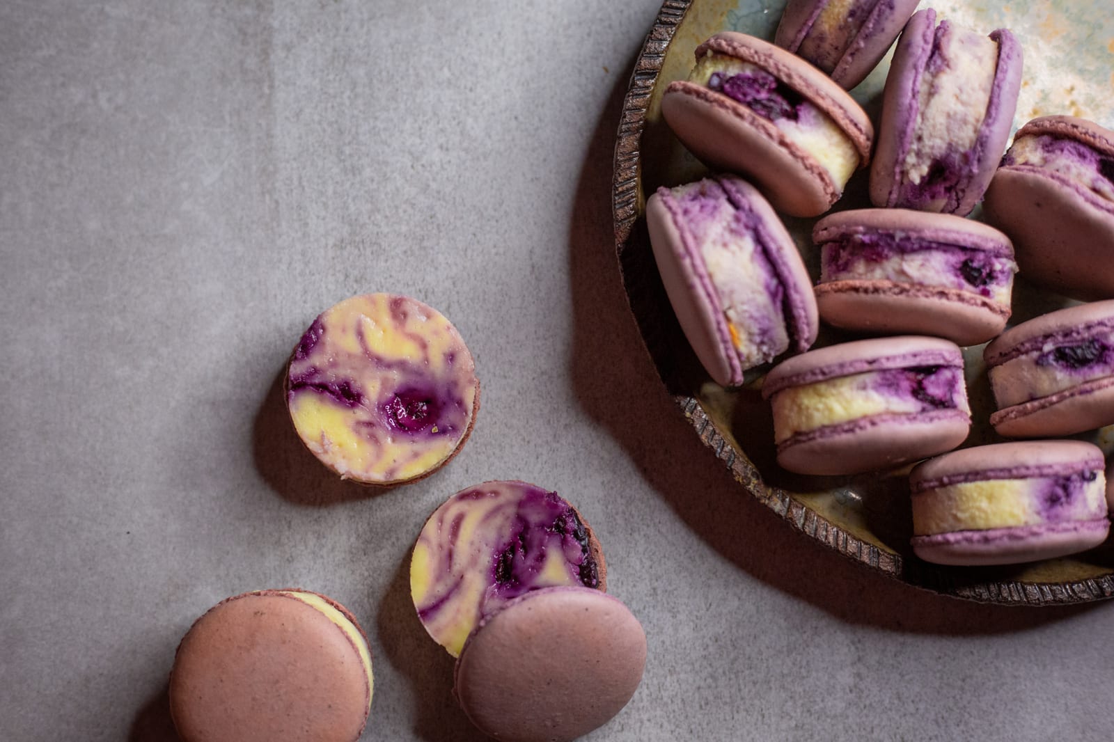 Blueberry cheesecake macarons showing their blueberry swirl filling beside the plate, from above