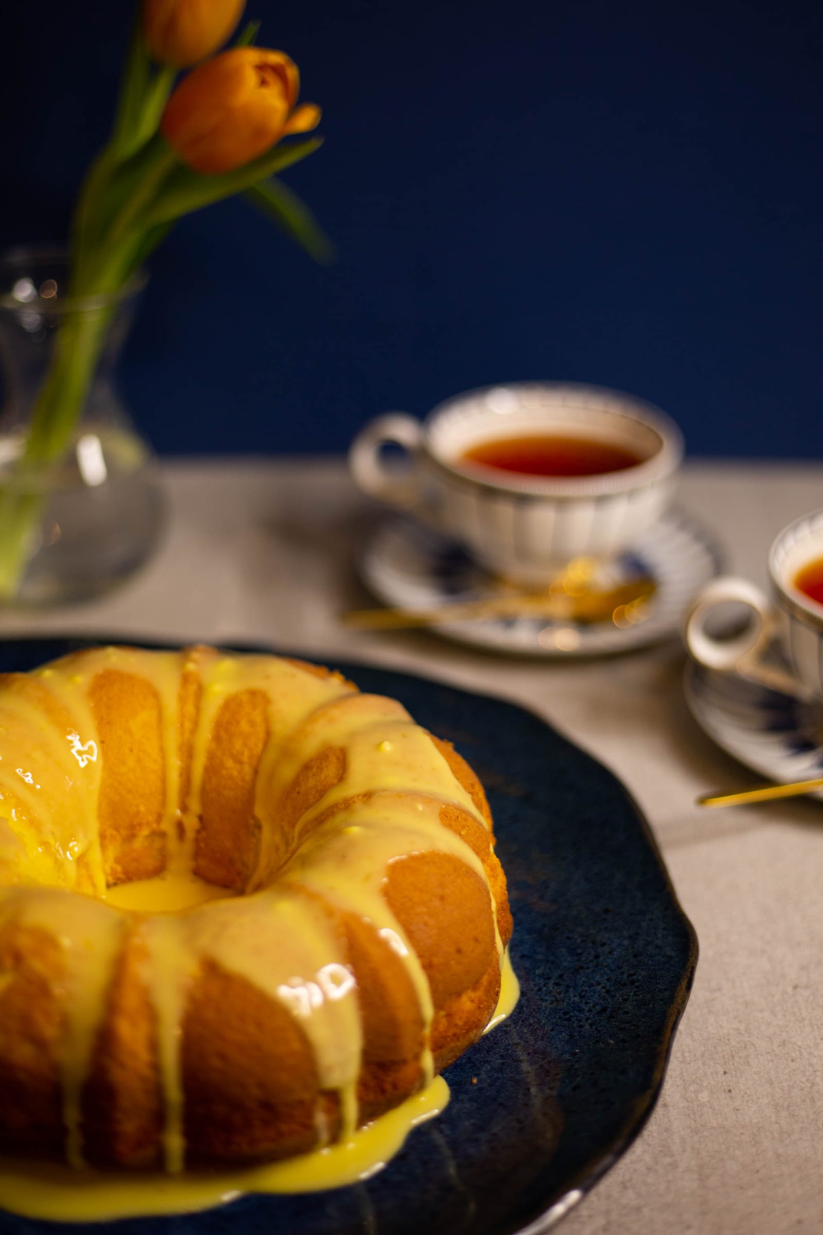 A glazed saffron milk cake with orange tulips and teacups