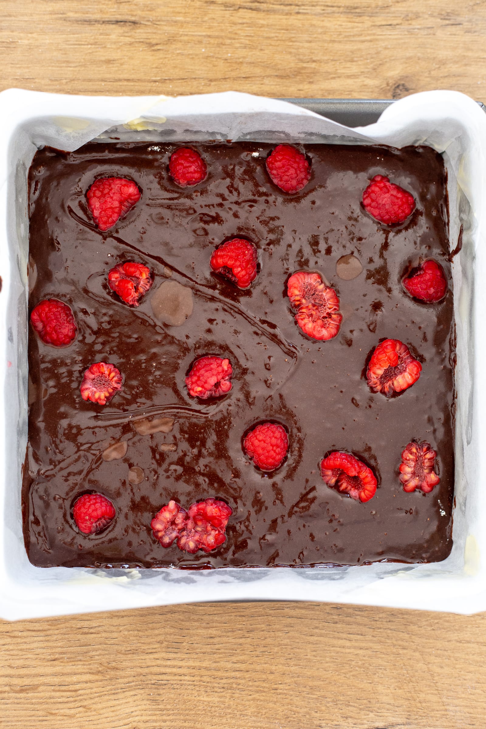 The brownie layer dotted with raspberries, before the cheesecake goes on