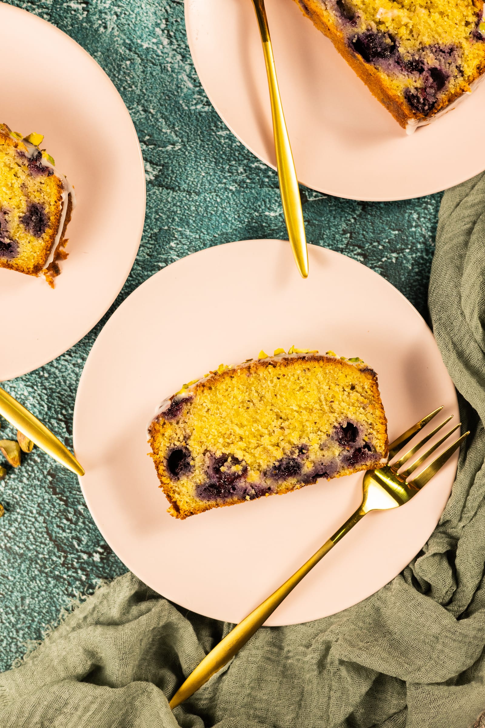 A slice of loaf on a pink plate with a gold fork, from above