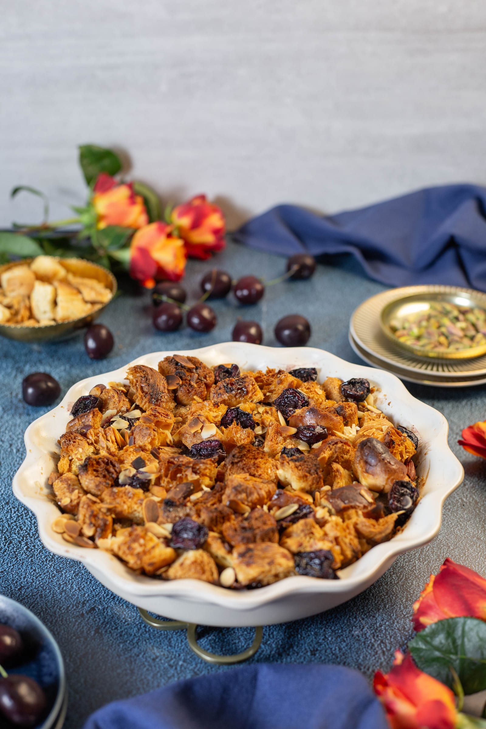 The bread and butter pudding in a scalloped dish, with orange flowers and cherries